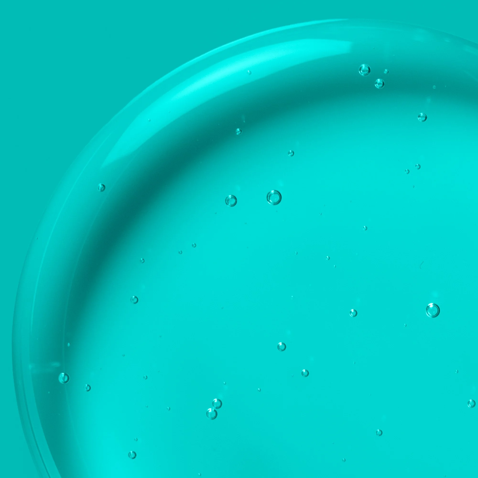 Close-up of bubbly liquid or gel with a teal background.