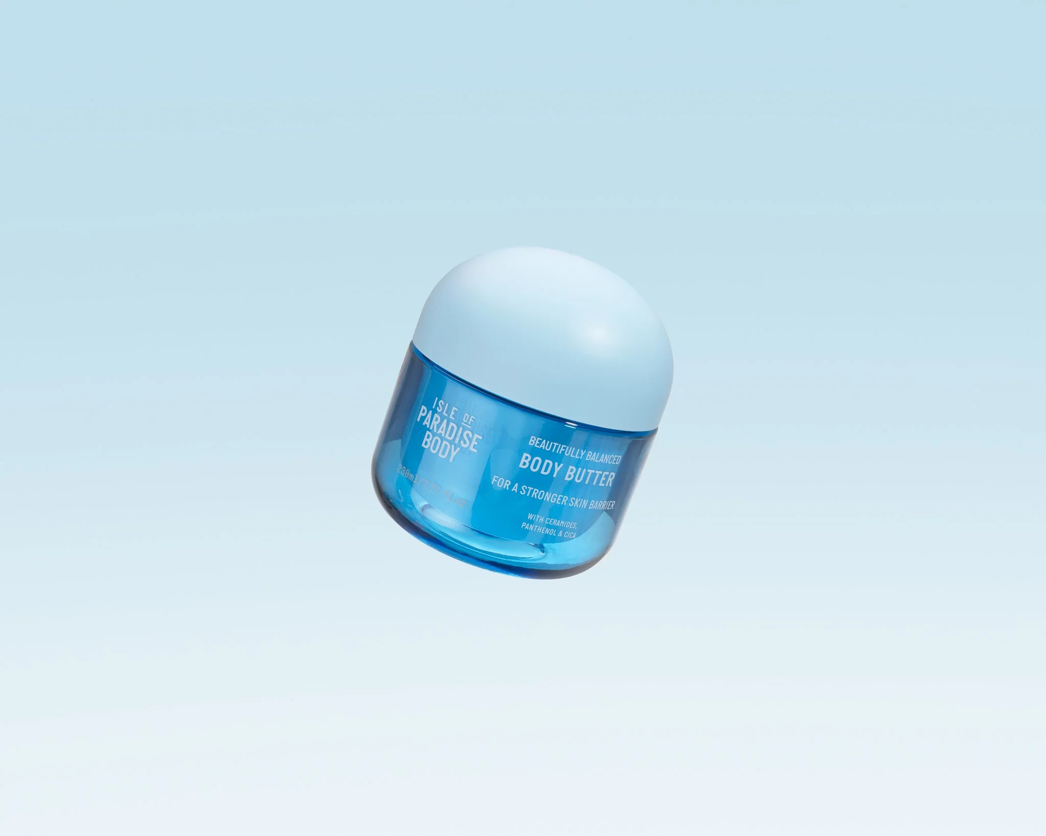 Blue jar of Isle of Paradise Body Body Butter with white lid, floating in a light background.