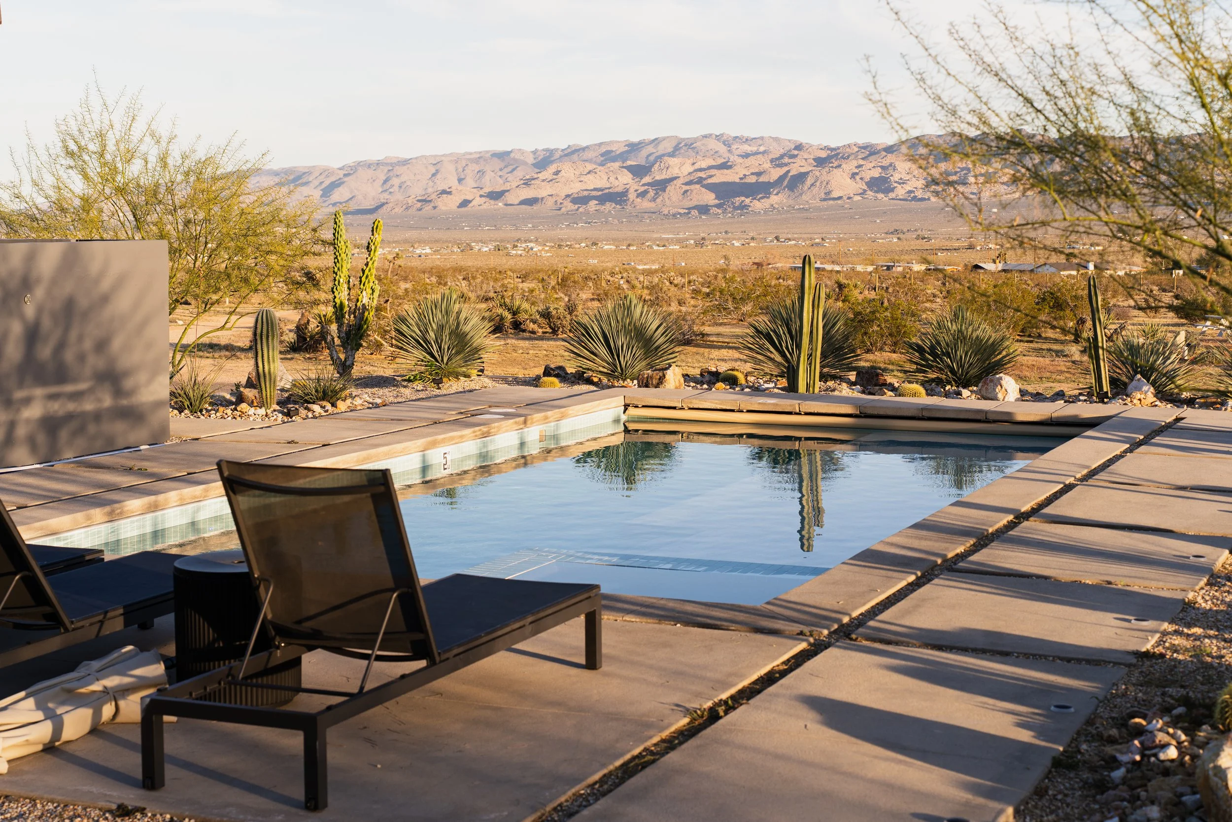 Pool surrounded by desert landscaping with spectacular mountain views.