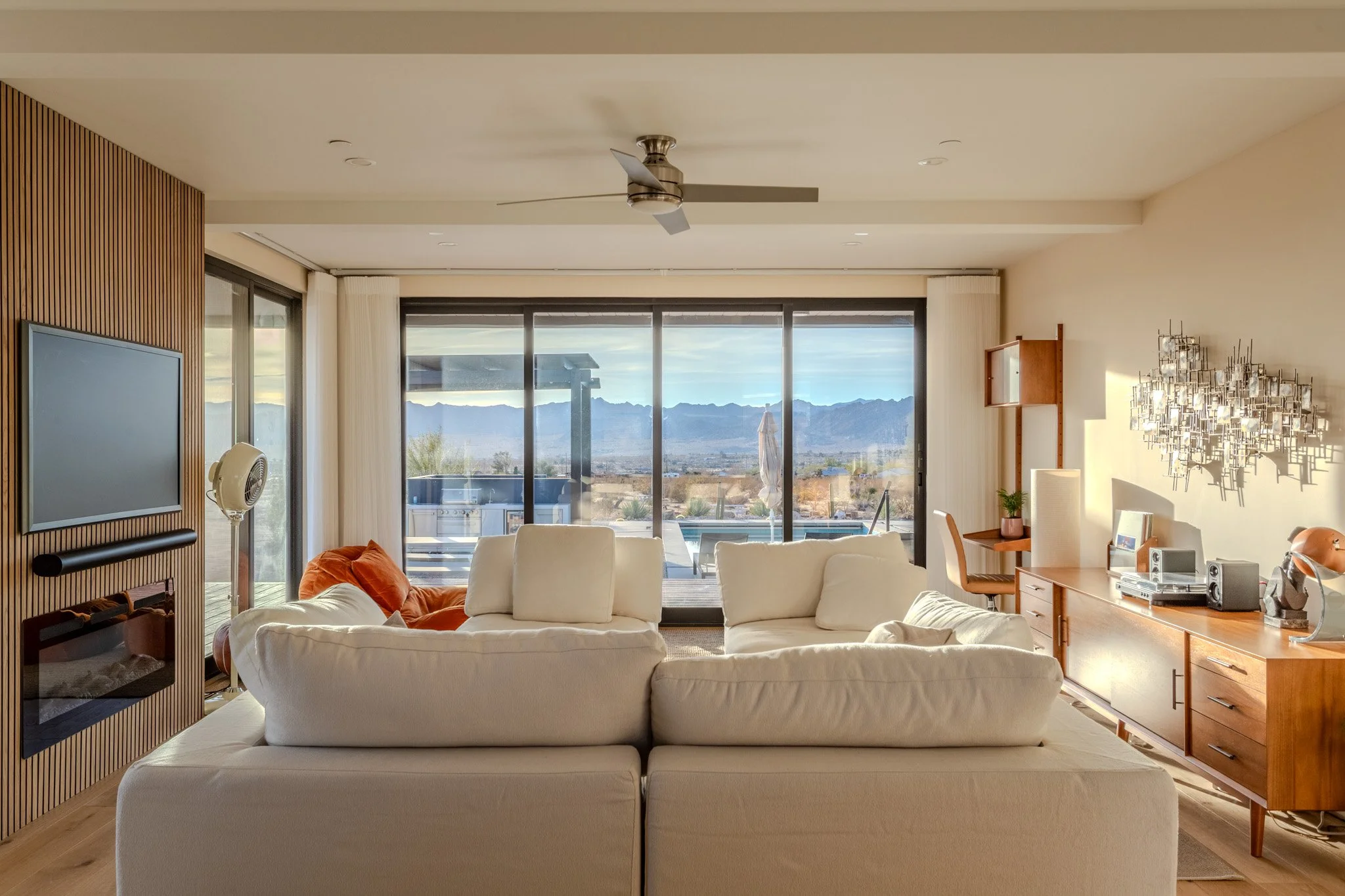 Living room with white sofa, wooden sideboard, and large sliding glass doors leading to outdoor patio with Mountain View