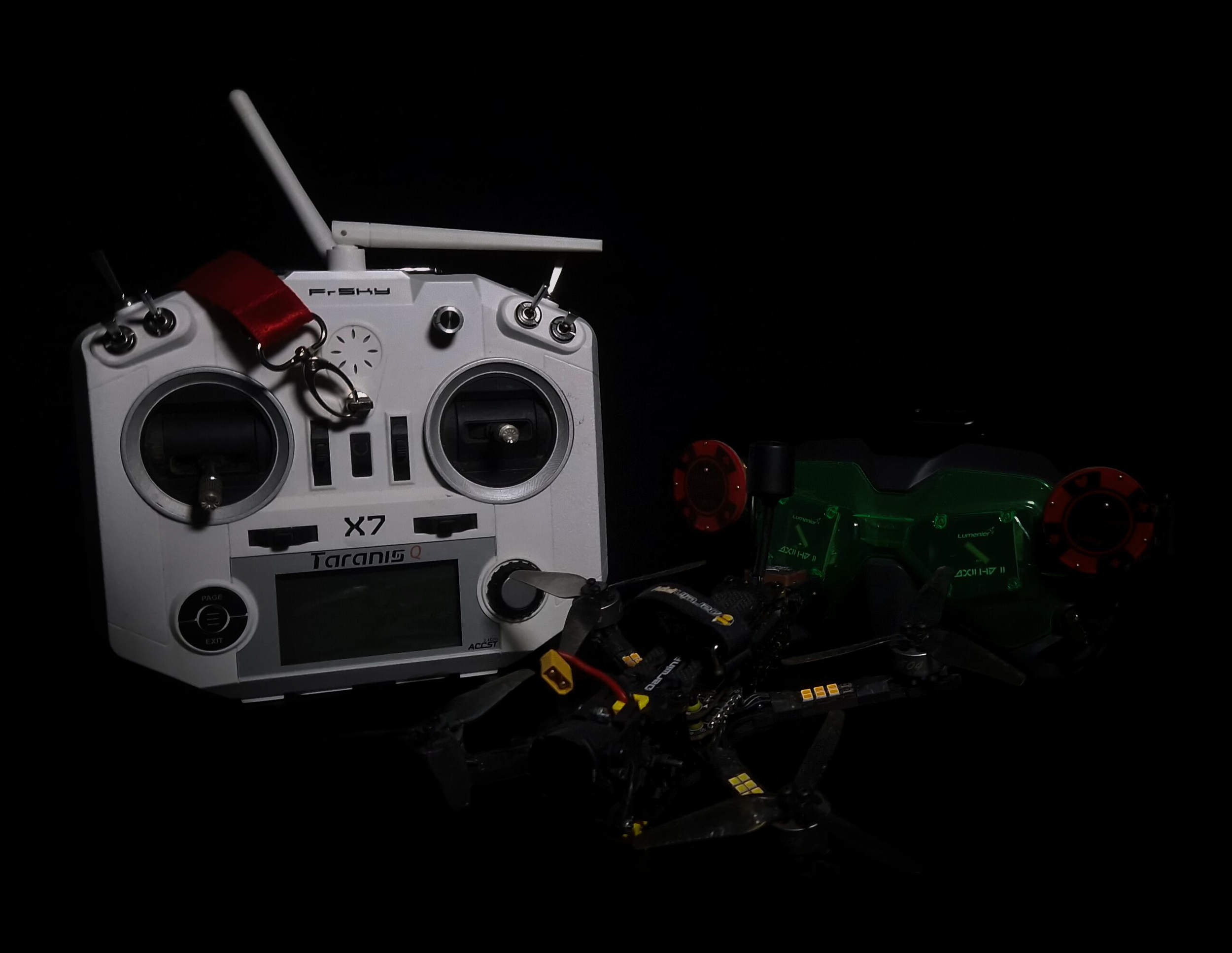 Ein FPV Copter mit Fernbedienung und Googles, vor einem dunklen Hintergrund.