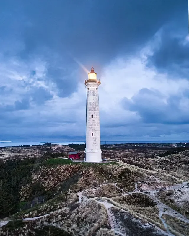 Leuchtturm auf einer Küstenklippe bei bewölktem Himmel