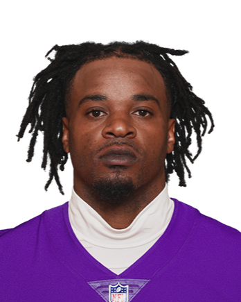 Close-up of a man with dreadlocks wearing a purple sports jersey