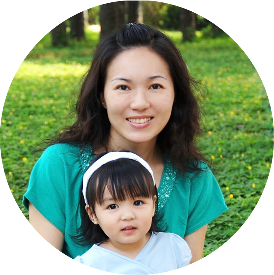 A young woman with wavy hair smiling, wearing a patterned dress and necklace, in black and white.