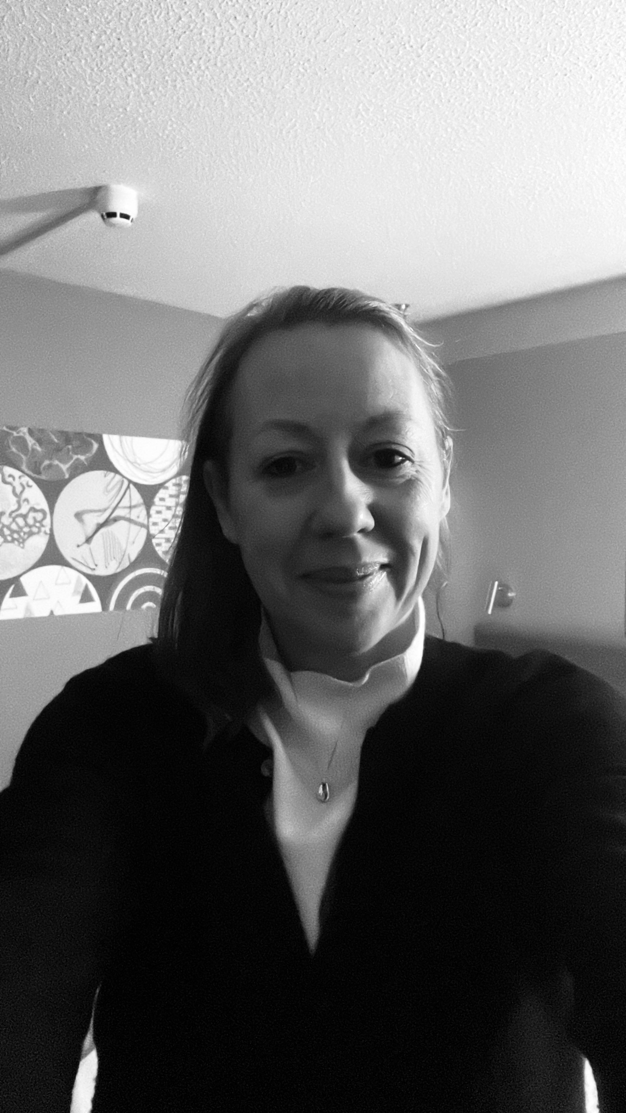 A woman taking a selfie in a room with lamp shades in the background.