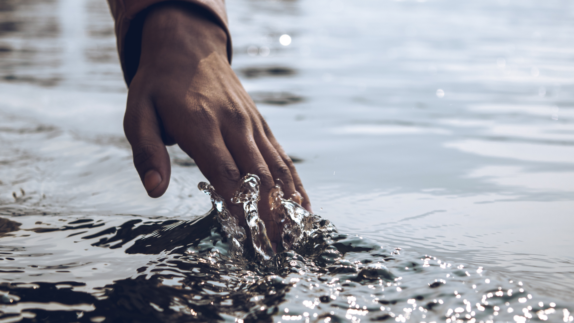 Hand running through water, feeling and experiencing aliveness.