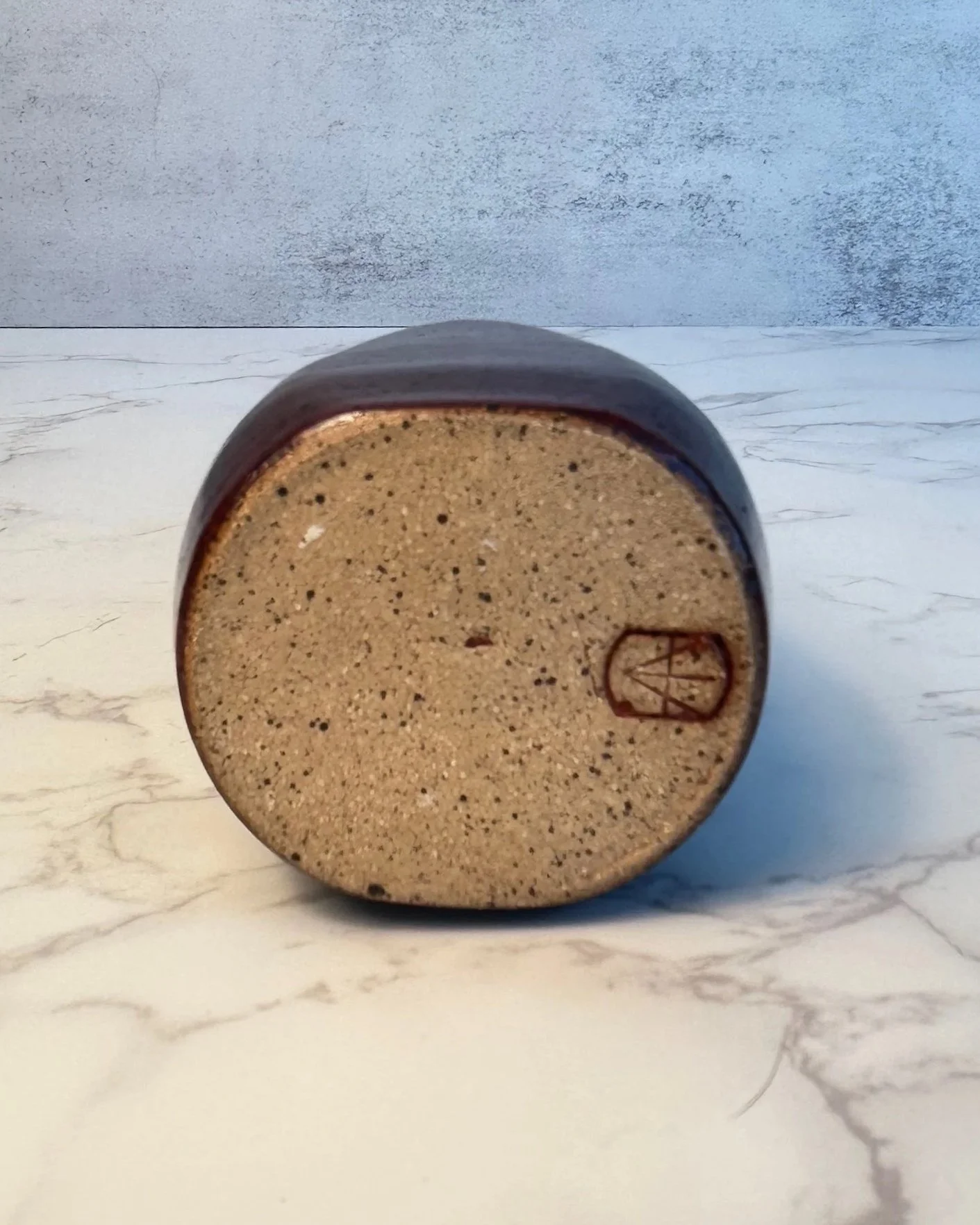 Bottom view of handmade ceramic oil bottle with stainless steel pour spout in deep red glaze