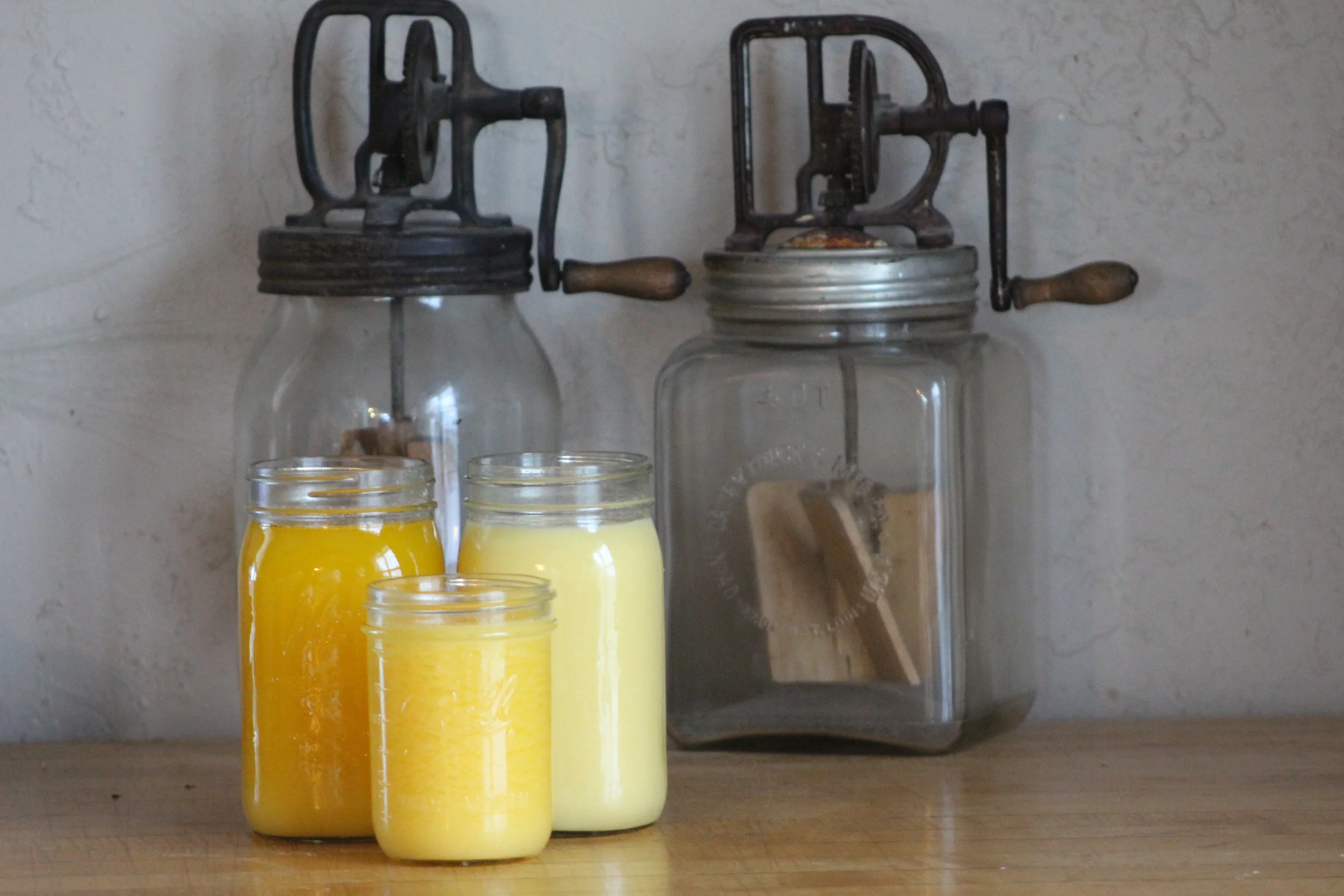 ghee cooling in jars with antique butter churns in the background