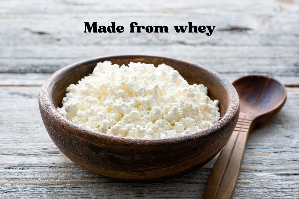 Fluffy white ricotta curds in a wood bowl