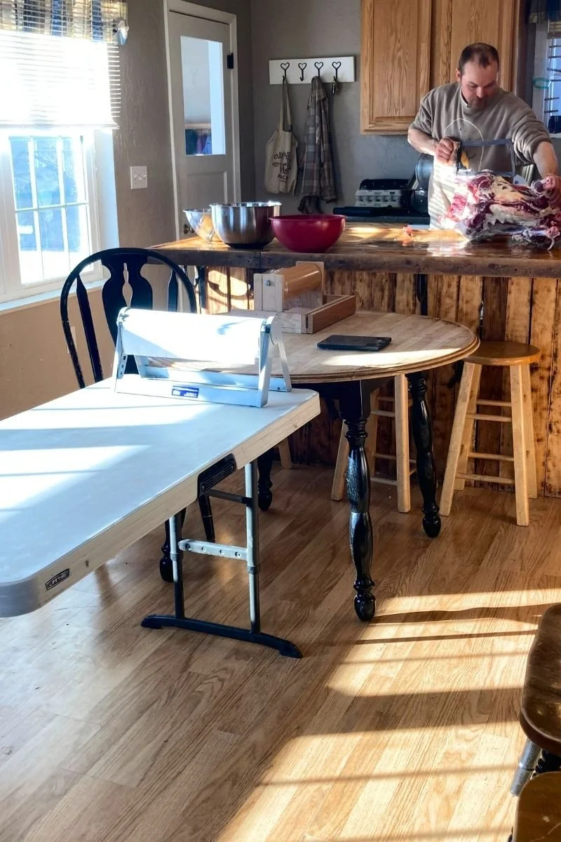 A man uses a bone saw to cut through the ribcage of a lamb carcass