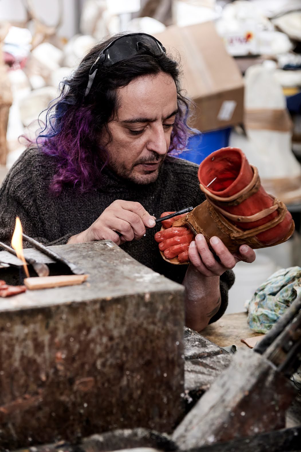 Leo Light Biaggi holding Hermes’ sculpted foot and working on its details at his studio workbench.