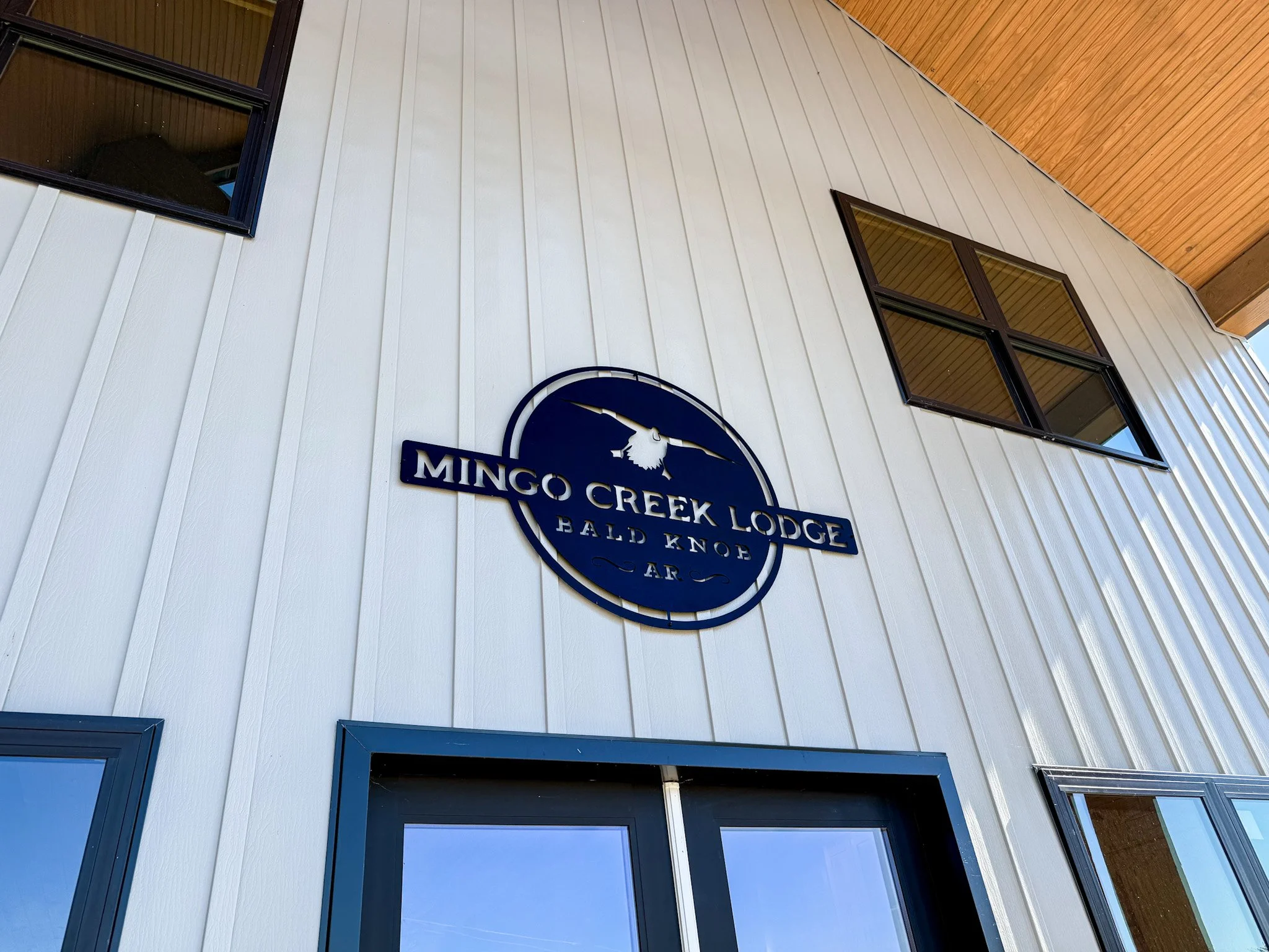 Metal sign for Mingo Creek Lodge Bald Knob AR, featuring a raven and a mountain scene.