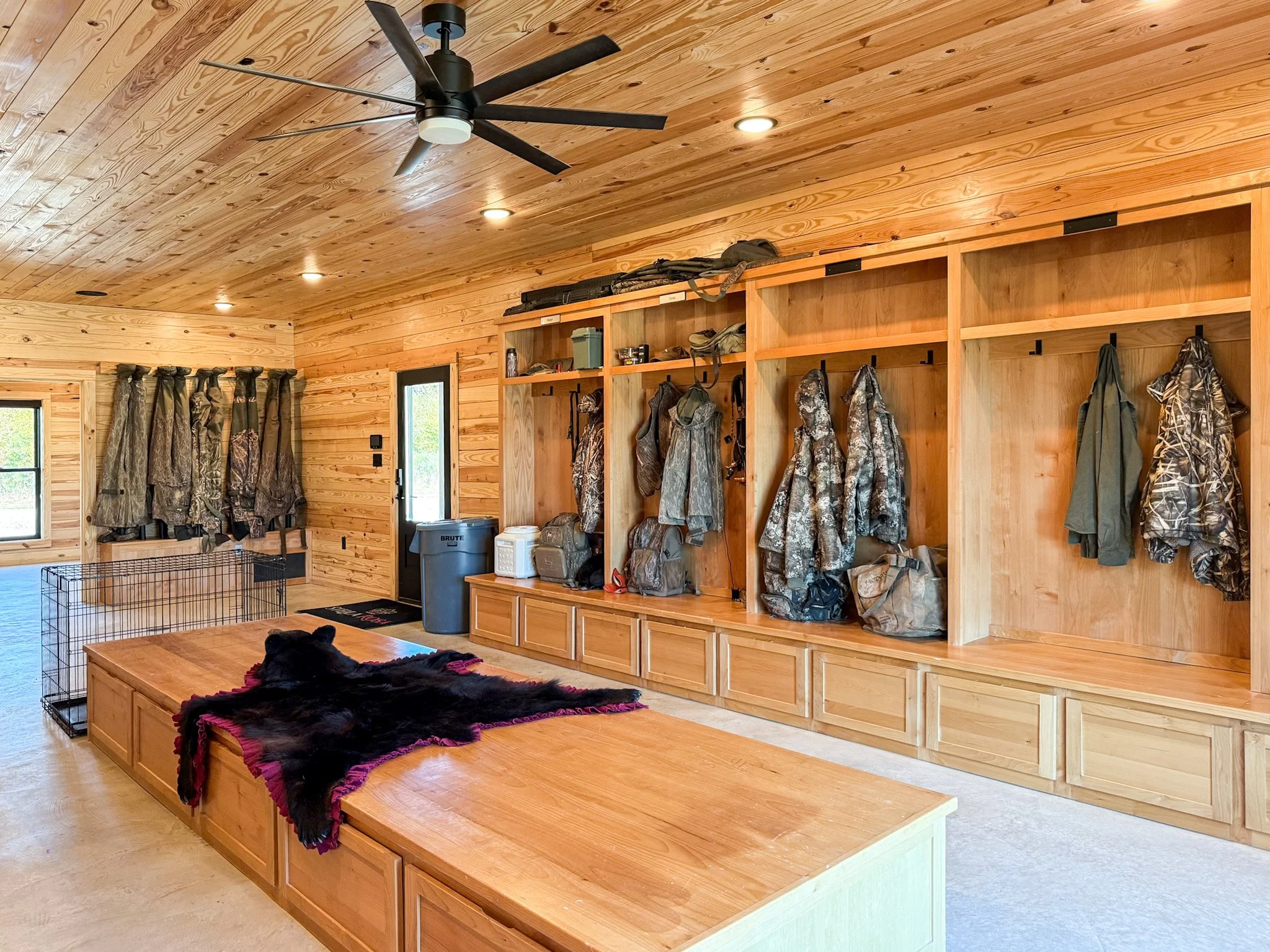 Empty wooden built-in shelves and cabinets in a room with a wood-paneled wall and a window.