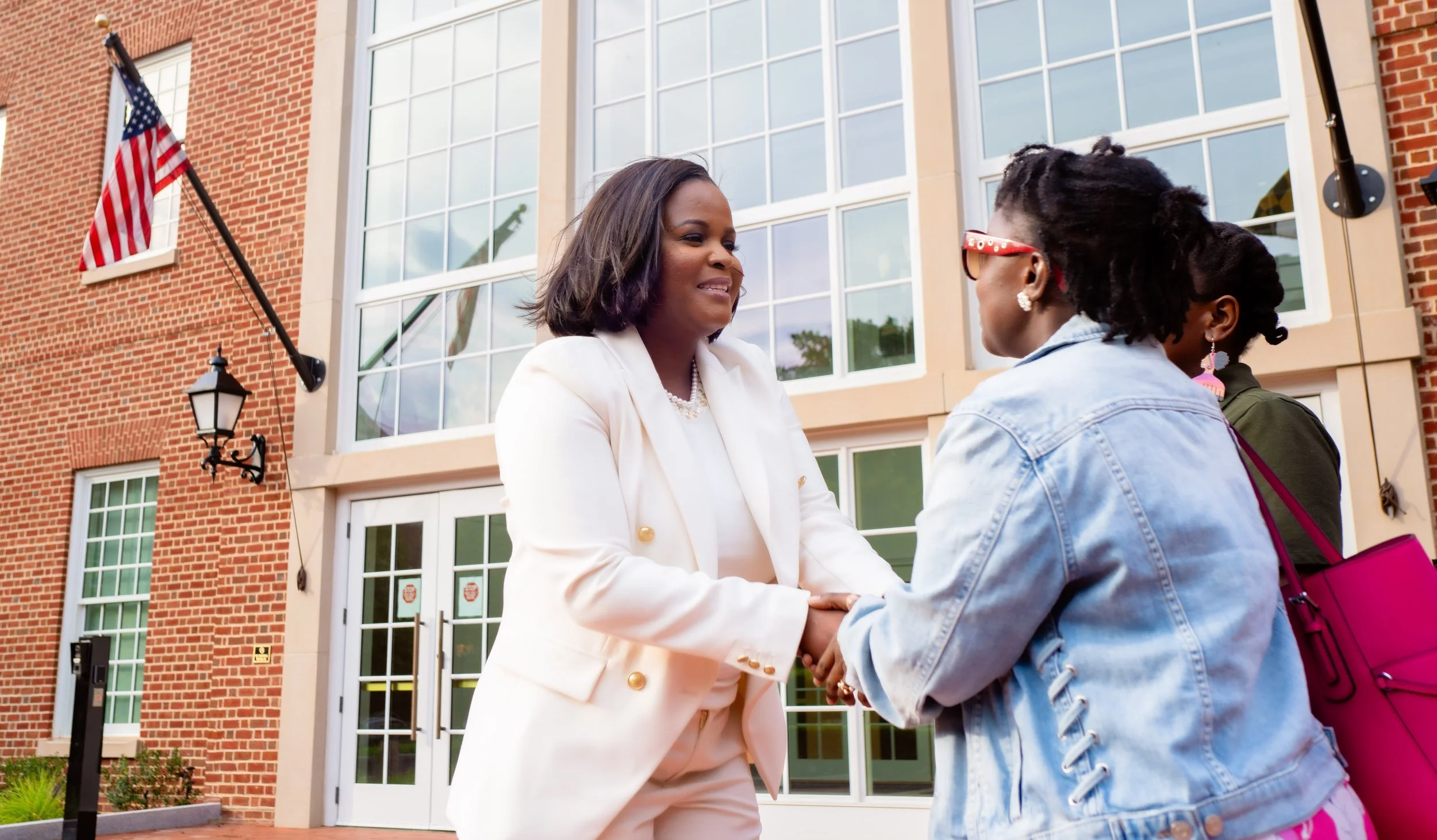 Quincy Bareebe shaking hands with two government employees, underscoring her commitment to protect civil-service pay and benefits