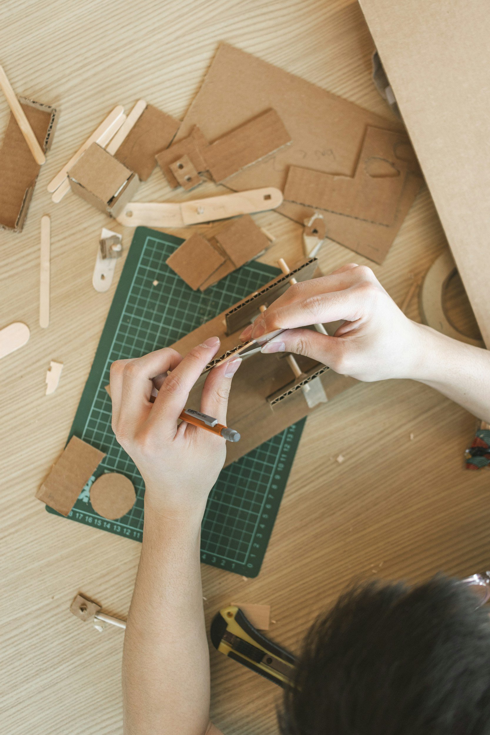 Image showing hands crafting with cardboard on top of a green cut mat.