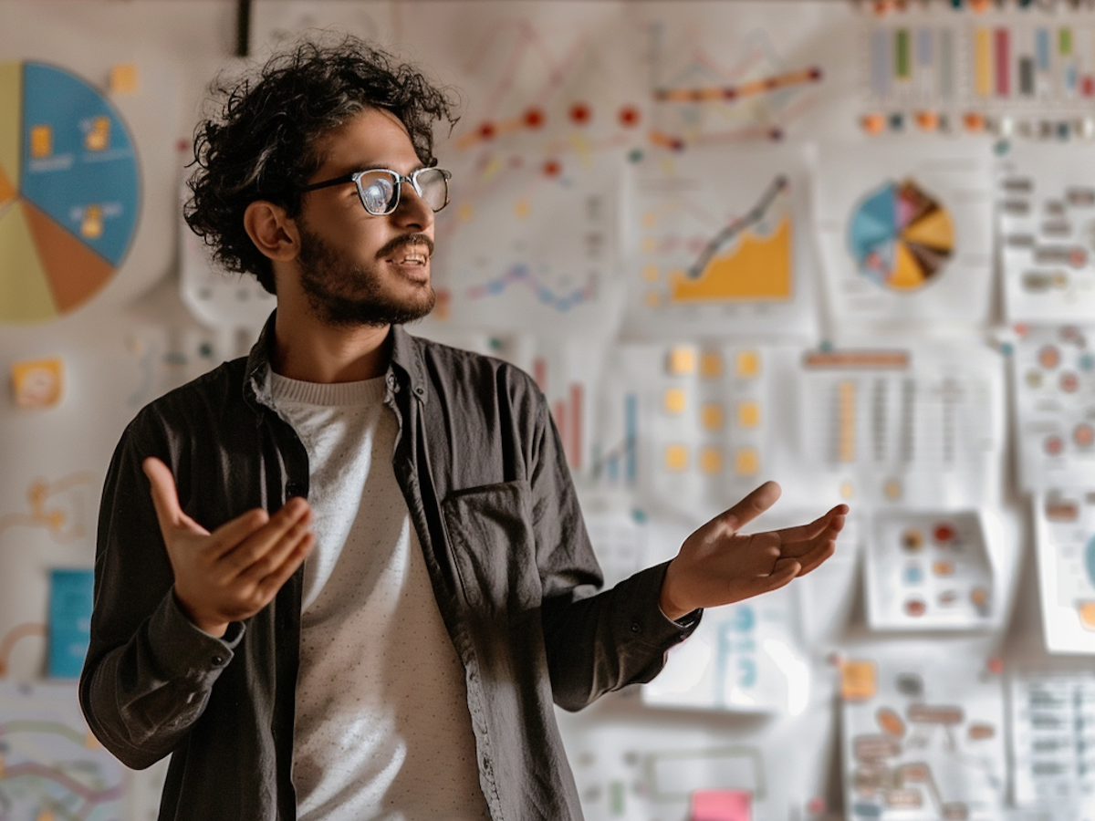 Person with curly hair gestures in front of colorful charts and graphs, suggesting a dynamic presentation setting reviewing metrics and ROI.