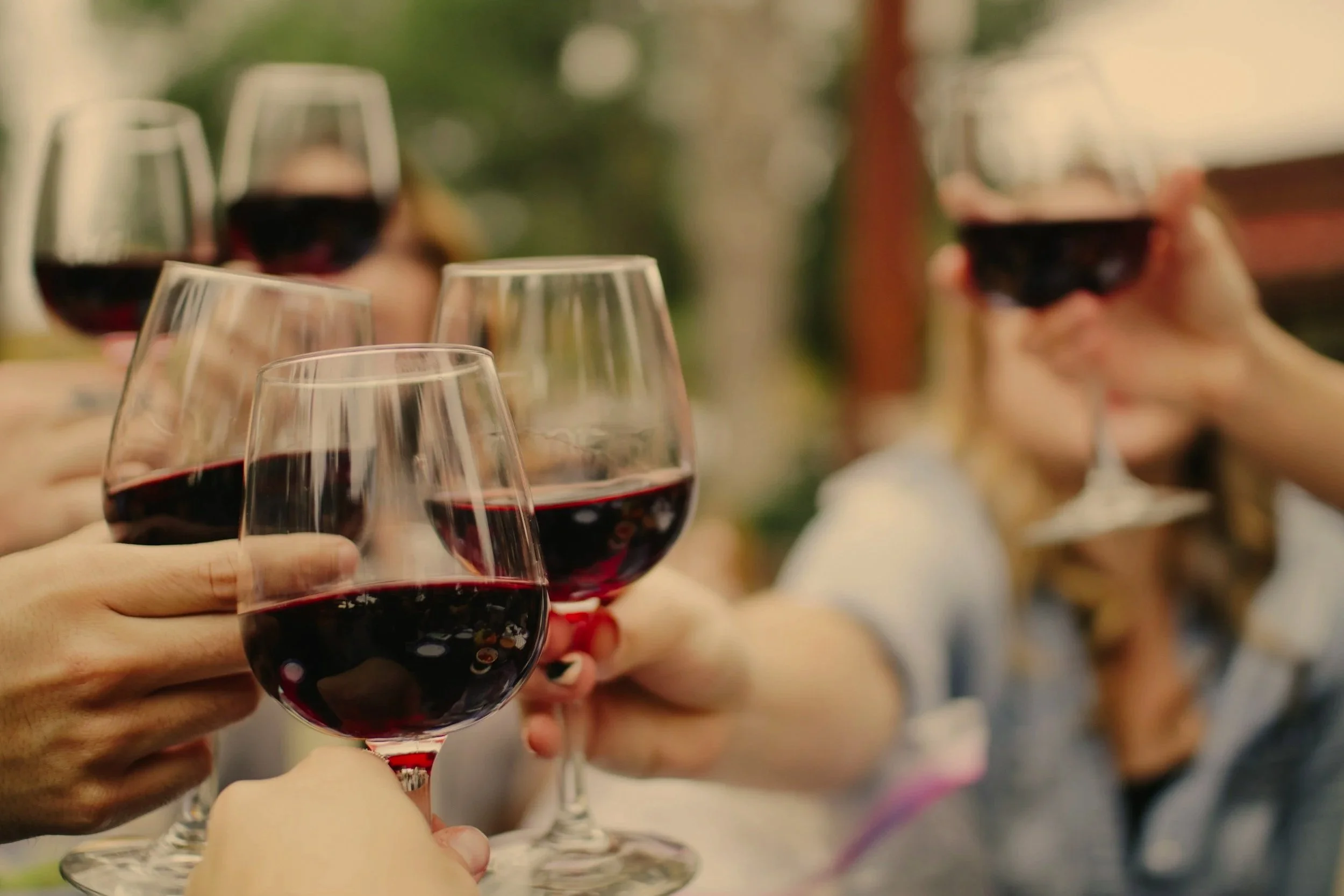 People clinking glasses of red wine outdoors
