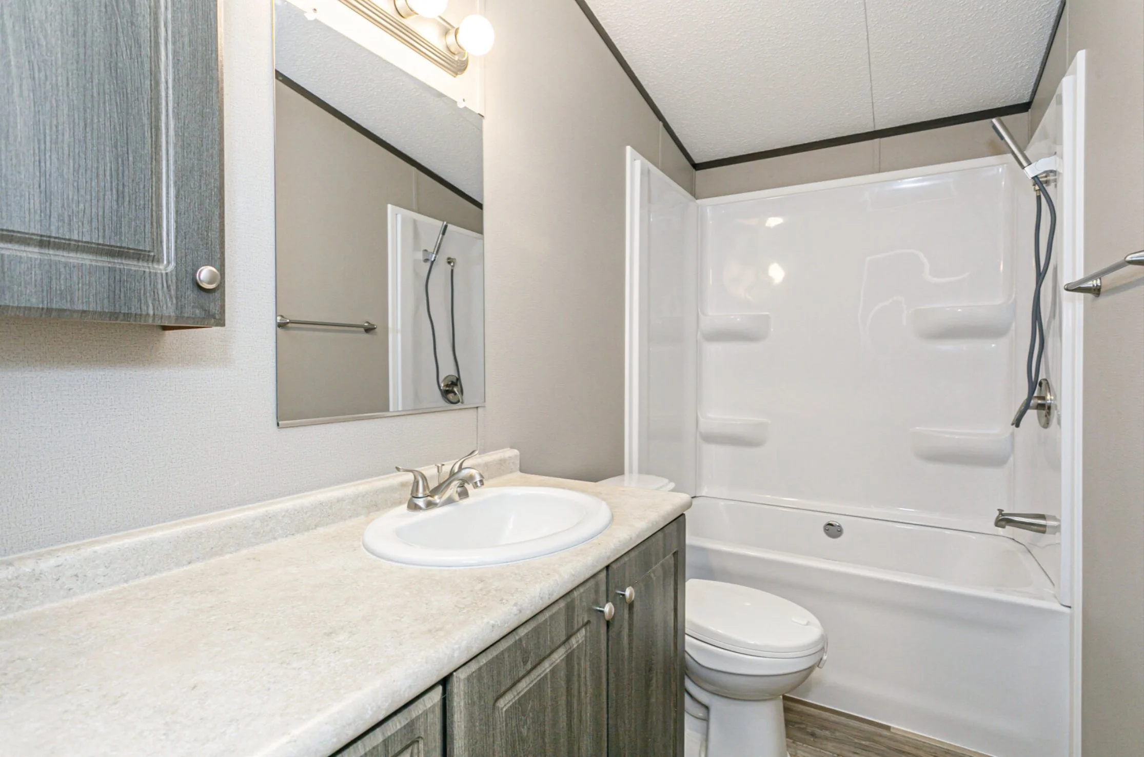 Bathroom with a sink, mirror, cabinet, toilet, and a shower with a white bathtub and shower panels.