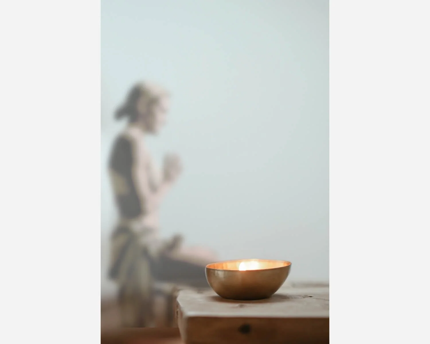 A person jogging with a focus on a lit candle in a copper bowl on a wooden surface in the foreground.