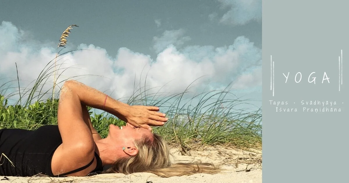 Yoga teacher Leslie Storms resting on the beach in South Beach, Miami, surrounded by sand and coastal grasses.