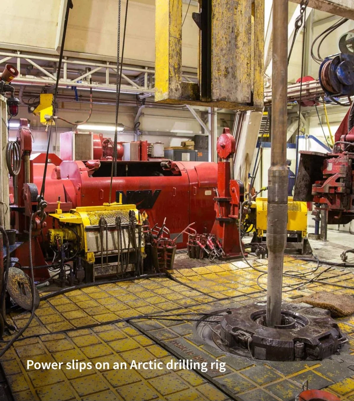 Power slips on an Arctic drilling rig with machinery and equipment surrounding a central drill pipe.