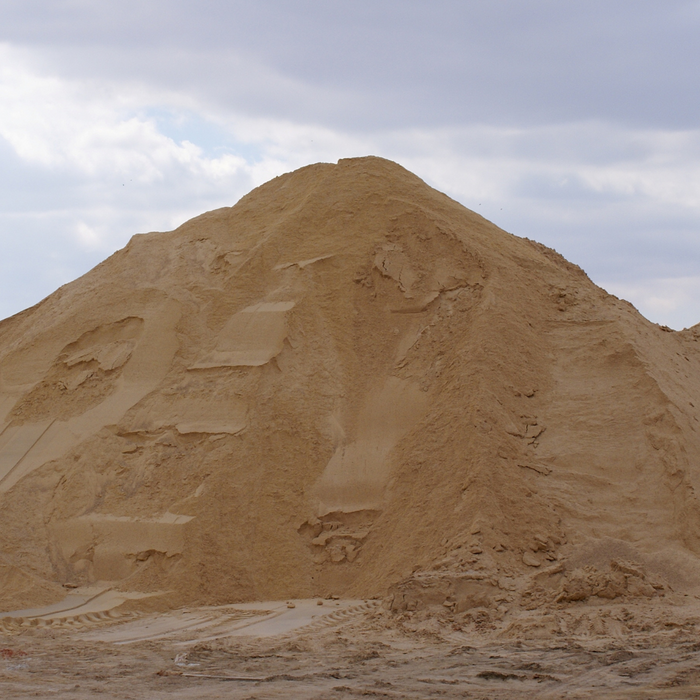 A large mound of sand or dirt with a cloudy sky in the background.