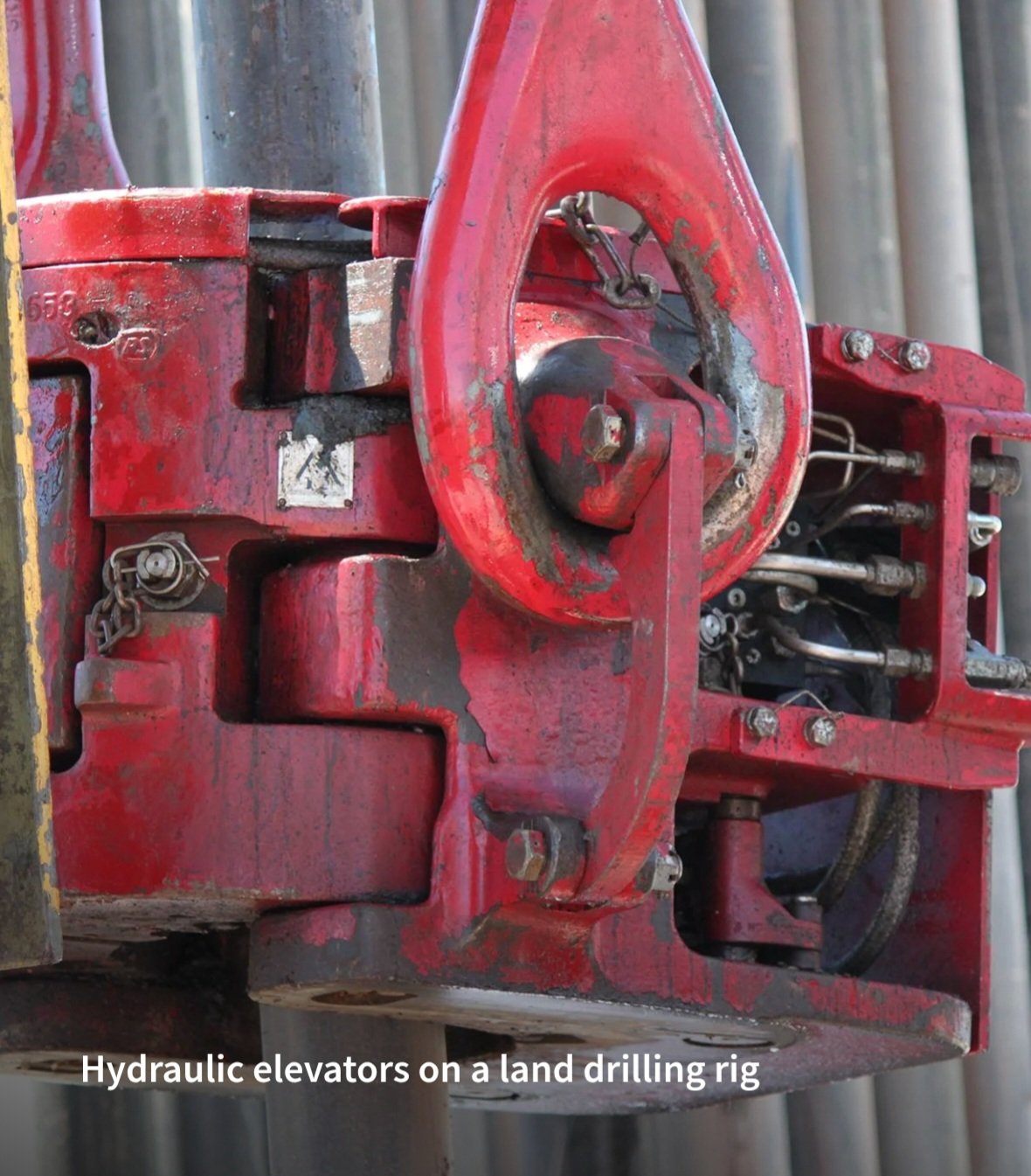 Close-up of hydraulic elevators with red paint on a land drilling rig, showing hydraulic components and metal parts.
