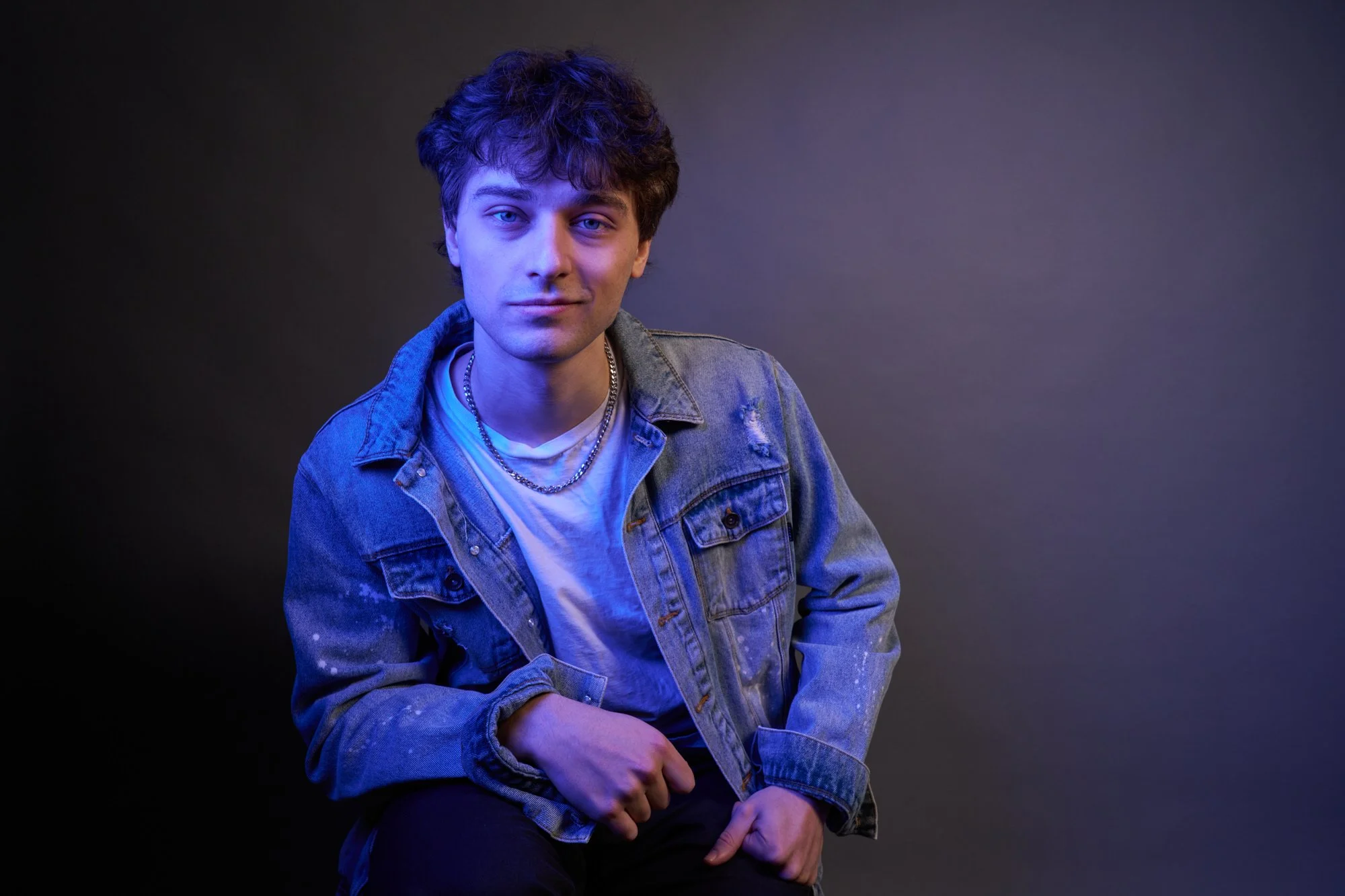 Color portrait of a man seated under blue studio lighting, direct gaze, photographed in Concord Massachusetts