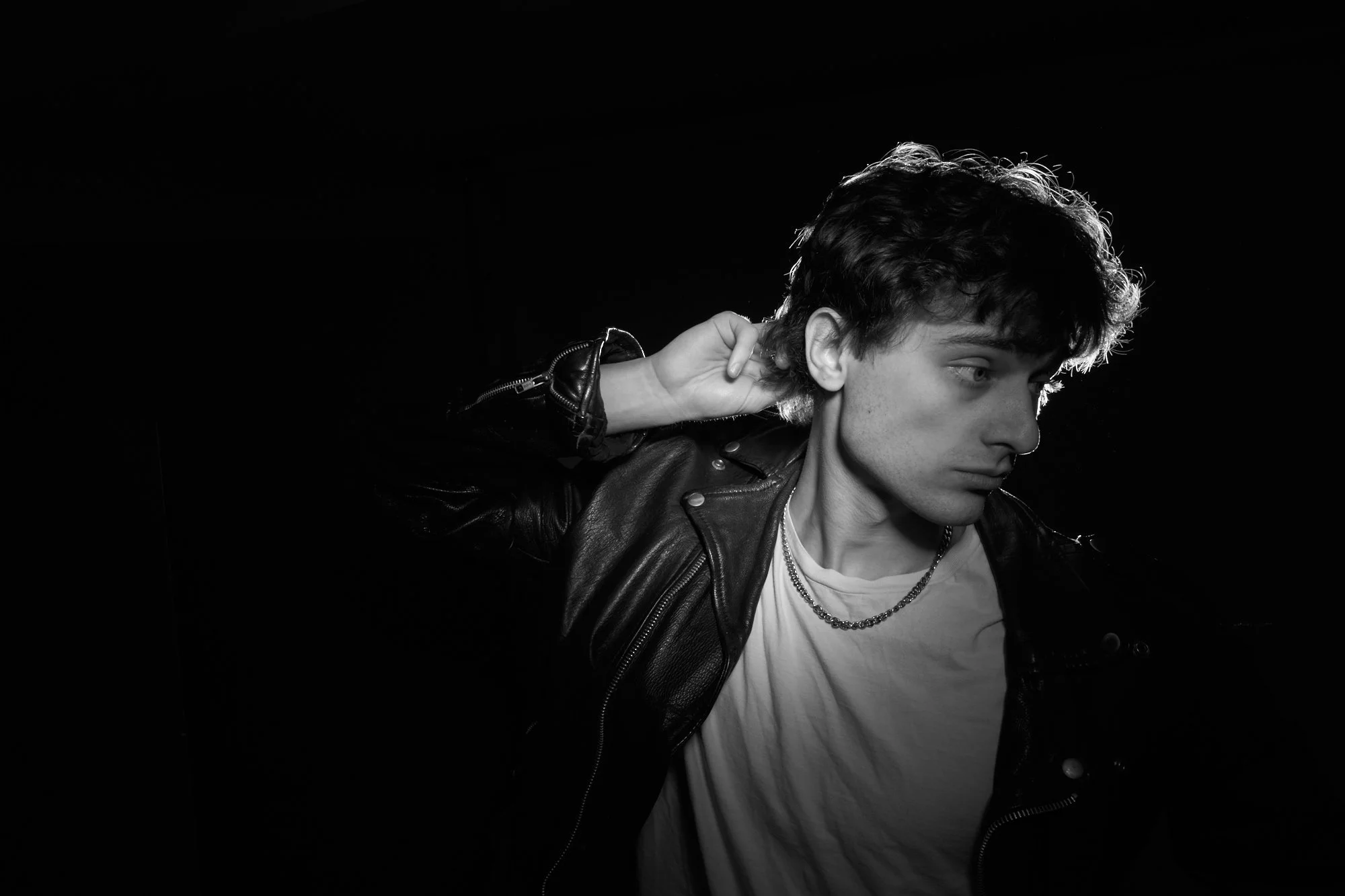 Black and white side profile portrait of a man in a leather jacket against a dark background, Concord Massachusetts studio