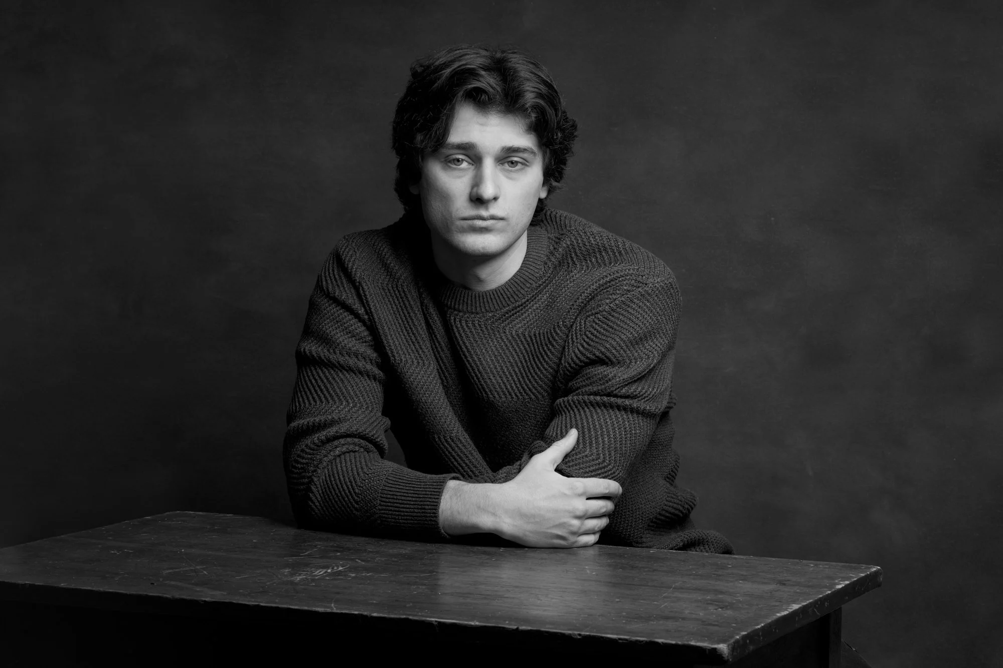 Black and white portrait of a man seated at a table, photographed in a studio in Concord Massachusetts