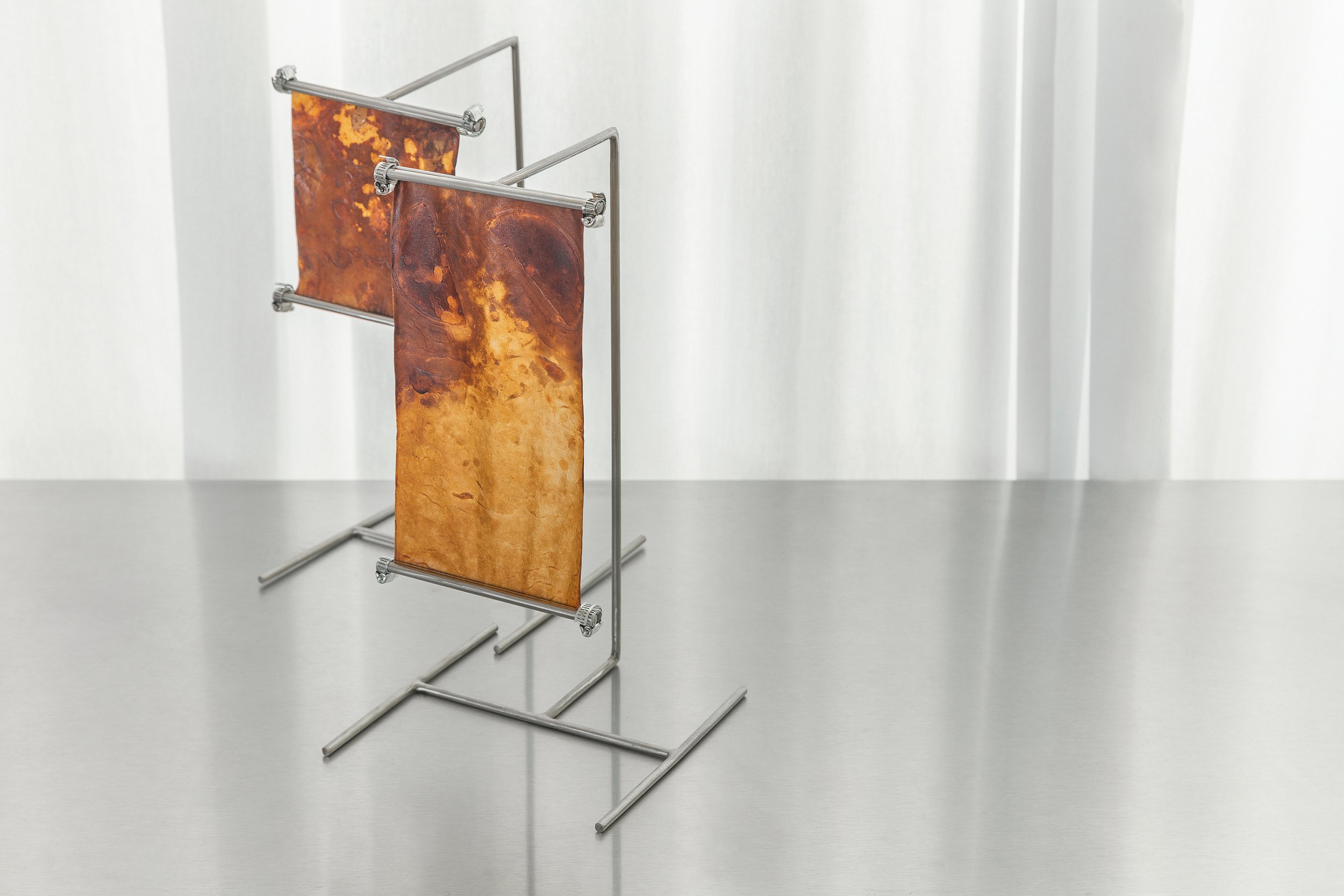 Designer floor lamp by Monterr Studio with a solid mycelium base and a translucent mycelium leather rectangular lampshade, emitting a warm golden light against a beige background.