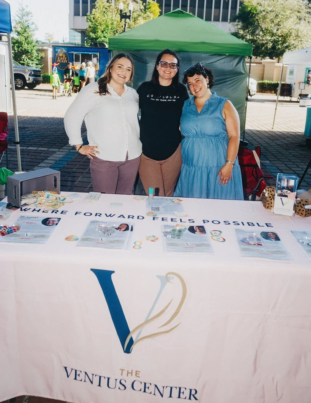 There female counselors standings behind a table with the Ventus logo