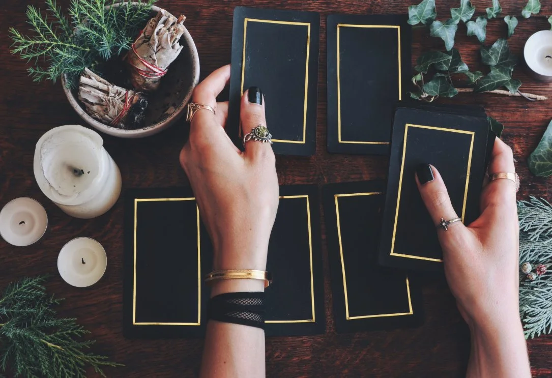 People doing a tarot card reading at a festive table decorated with candles, greenery, and holly.