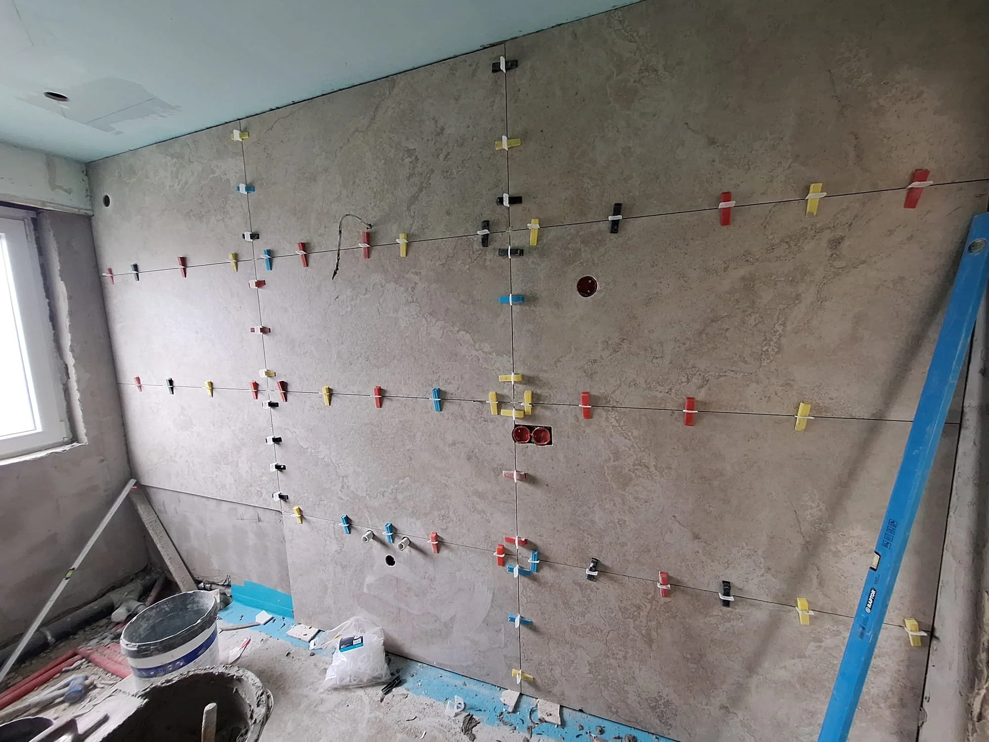Een keuken met een gootsteen, een zwarte kraan en een houtharige betegeling op de muur.