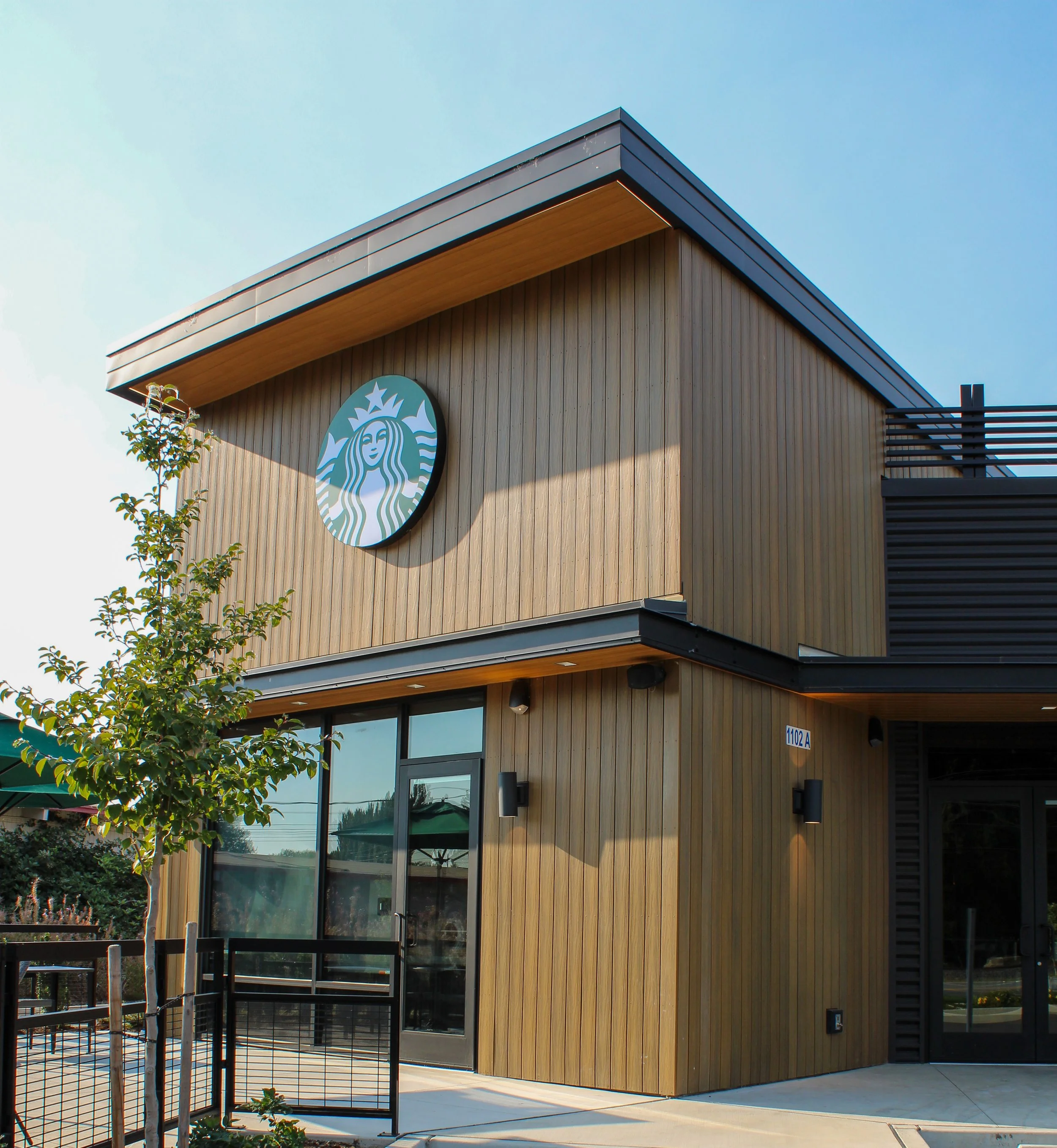 Modern building with wood siding, large glass windows, and a Starbucks logo on the wall.