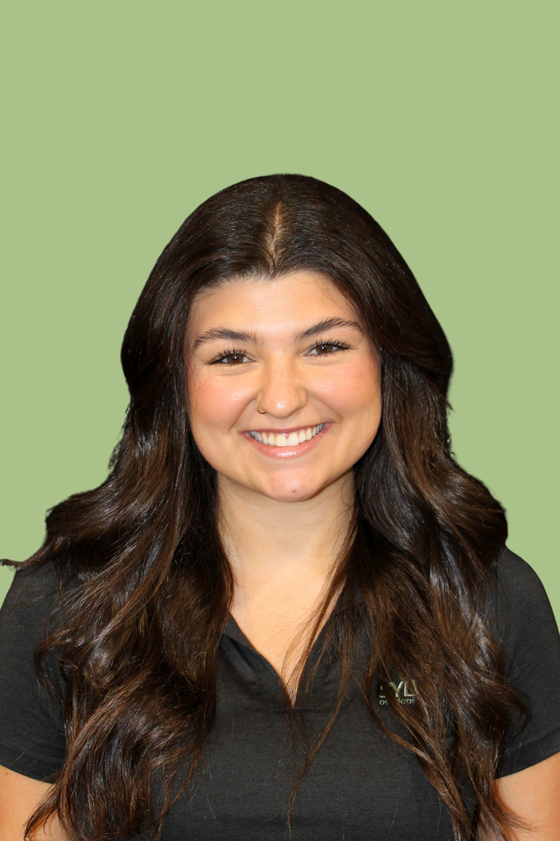 Portrait of a smiling woman with long dark hair, wearing a black shirt, and a green background.