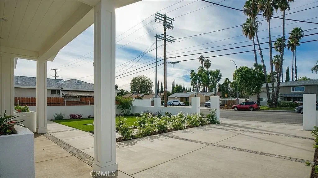 Driveway and front yard with columns and palm trees under a blue sky