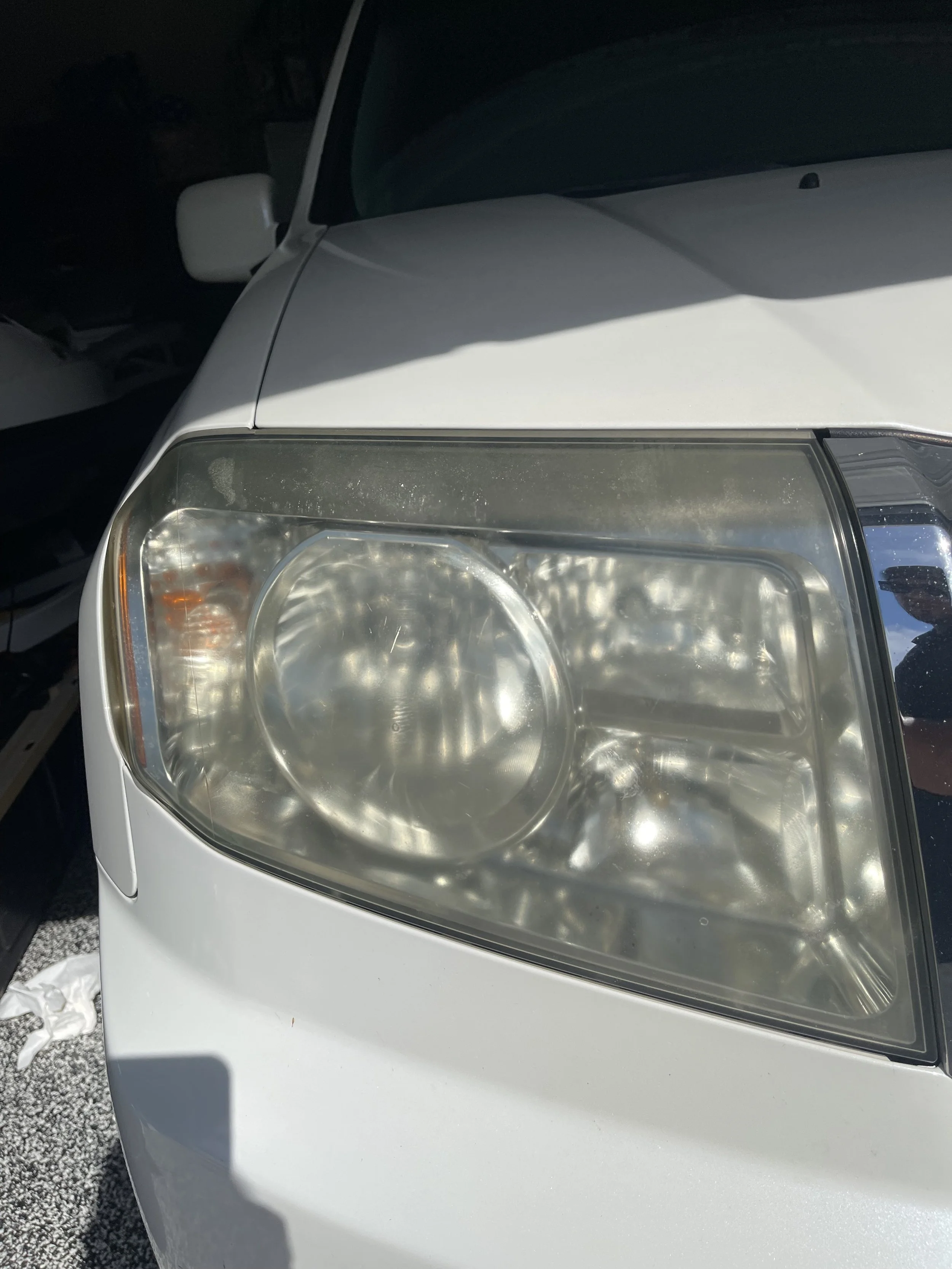 Severely oxidized and yellowed headlight with heavy cloudiness and UV damage, resulting in reduced clarity and diminished light output.