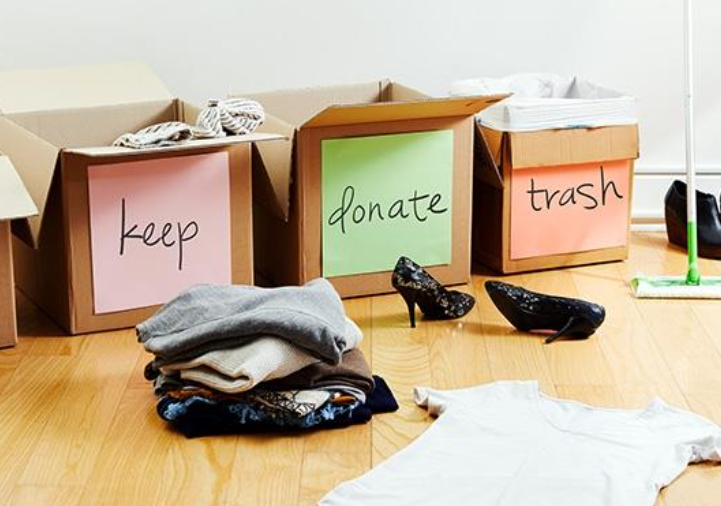 Boxes labeled 'keep,' 'donate,' and 'trash,' with clothes and shoes before organization or decluttering.