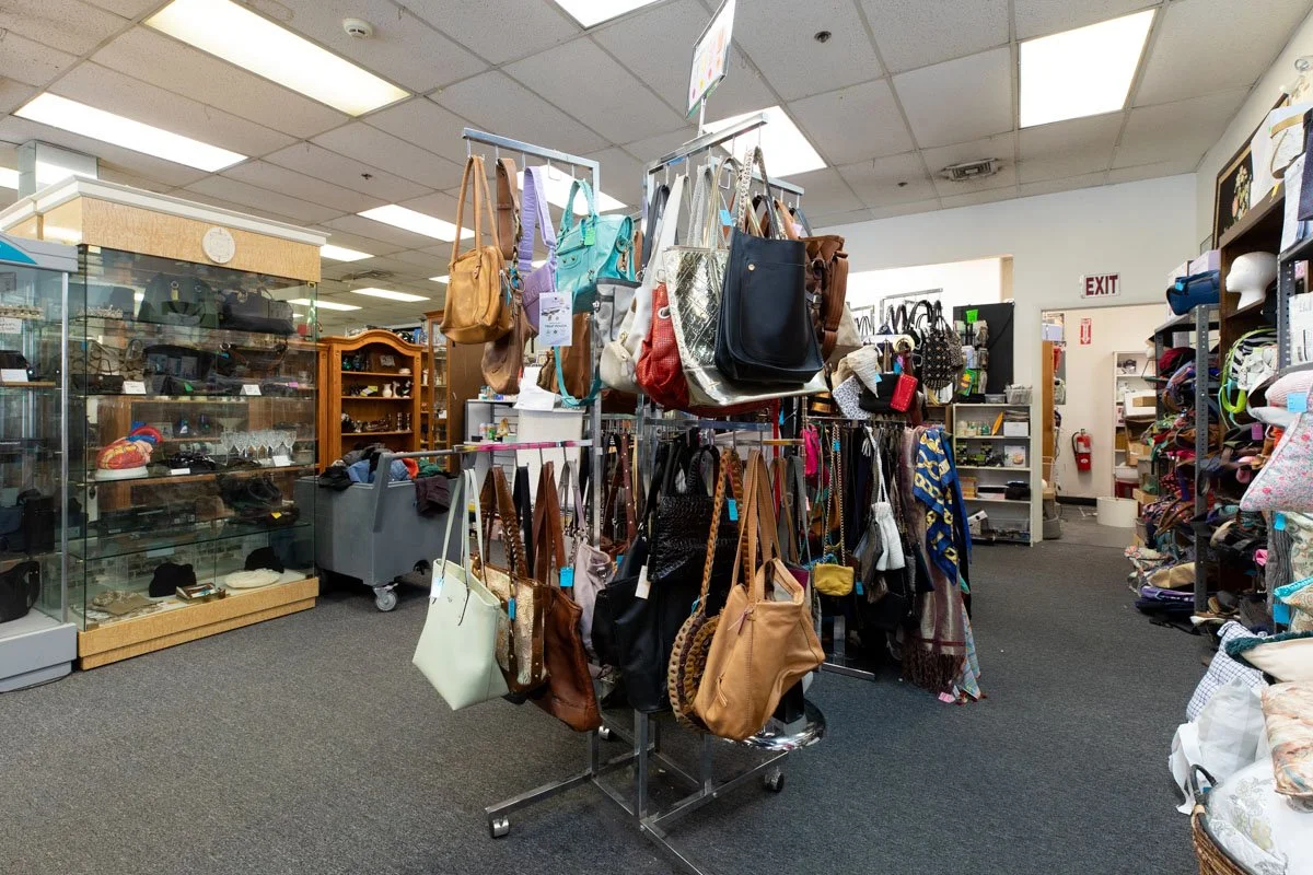 A display rack filled with various handbags and purses in a thrift store or consignment shop.