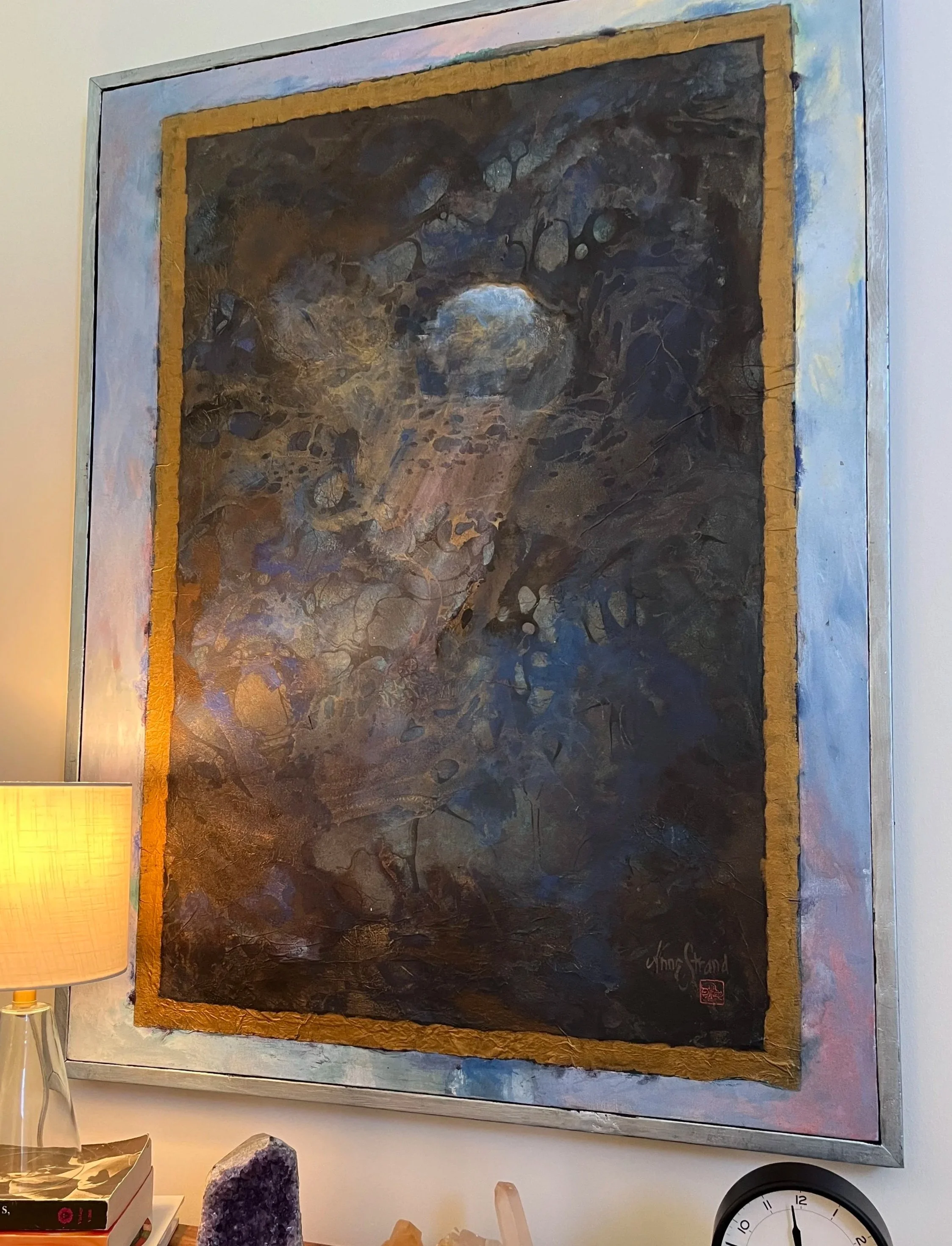 Artwork from office of Jamie Alvey, Brainspotting therapist. Painting by Anne Strand titled “View from the Cave.” A framed abstract painting with dark swirling colors, gold borders, and a signature in the bottom right corner, hung on a wall.