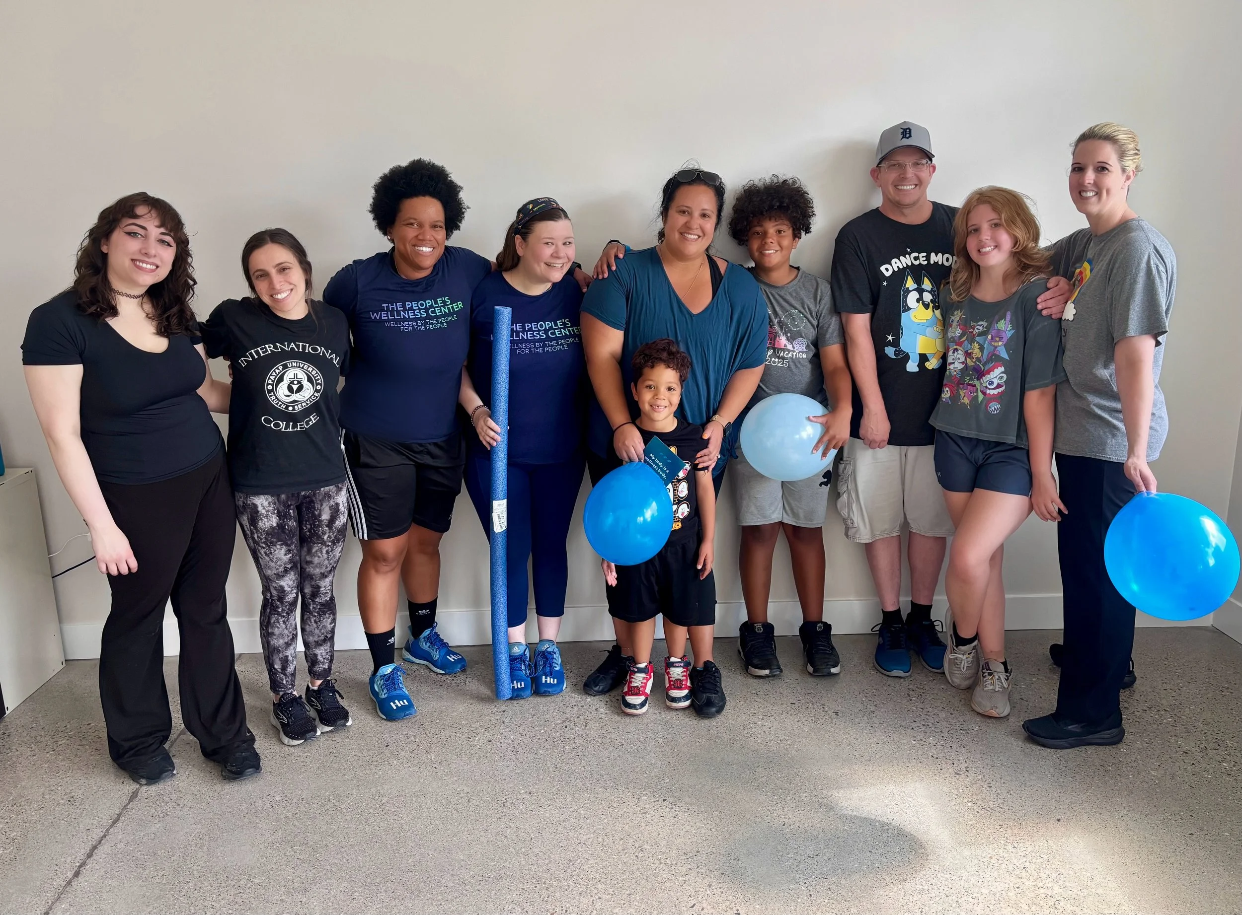 Families and adults smiling together at a People's Wellness Center community class