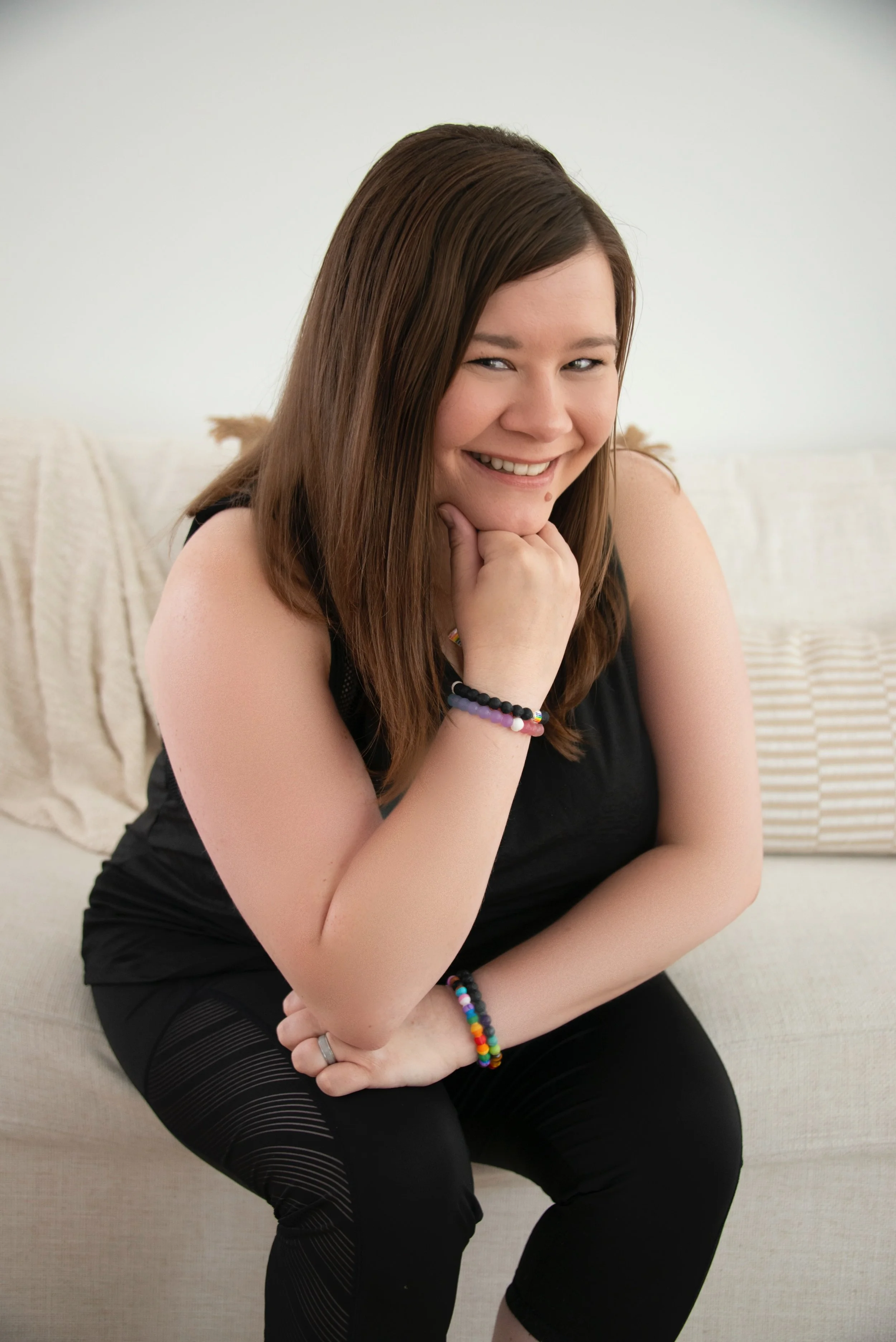 Rachele Rose, Reiki Master and yoga teacher, smiling while seated on a sofa