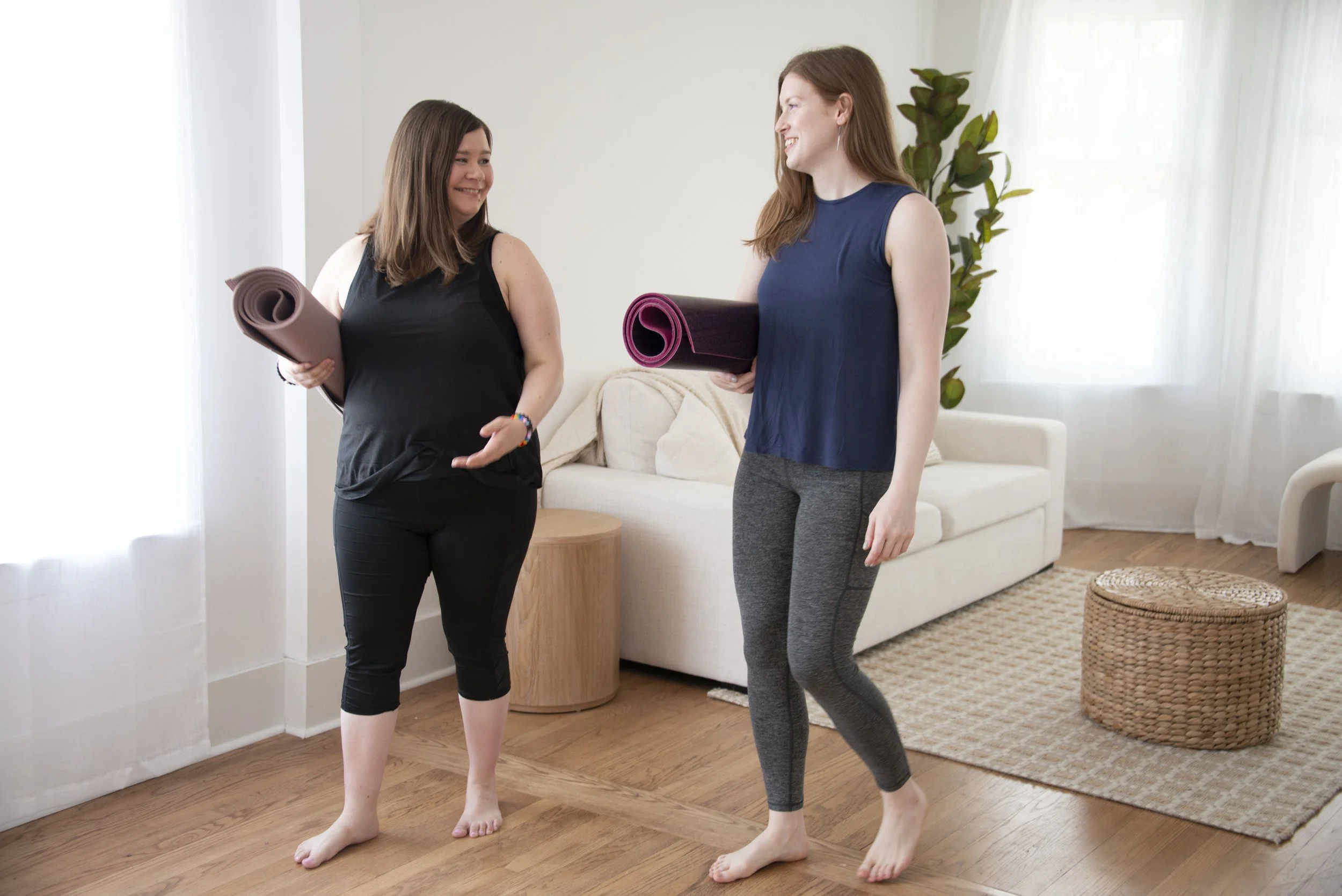 Rachele Rose and a student carrying yoga mats in a bright studio