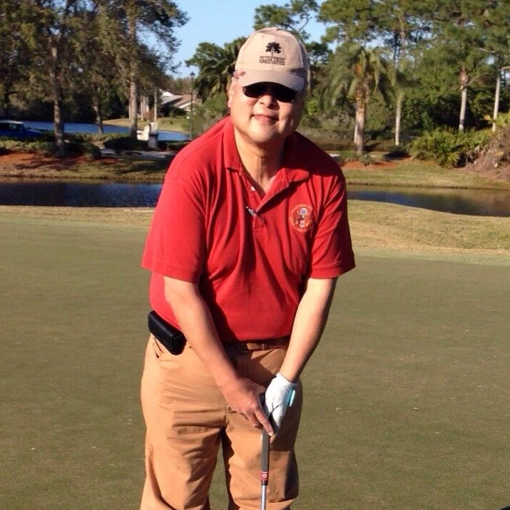 Alice Chen's father playing golf in chinos and a red shirt, capturing a moment of joy and personality from the family story behind The Unlearning Studio