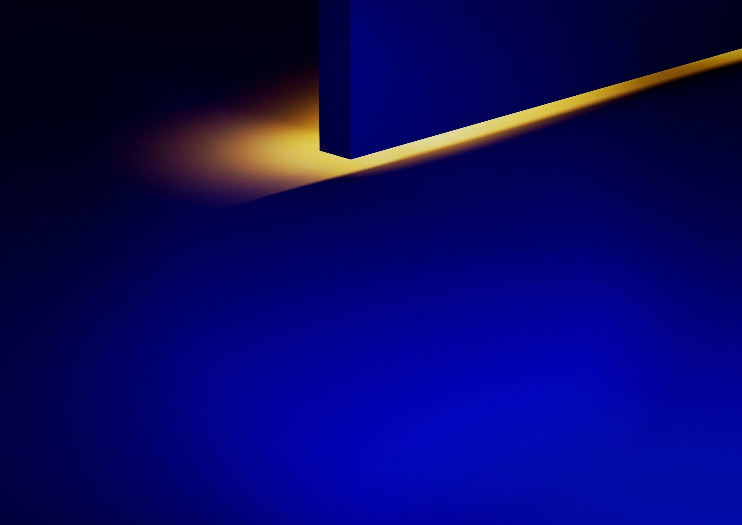 Close-up of a blue rectangular object with soft yellow lighting illuminating its edge against a dark blue background.