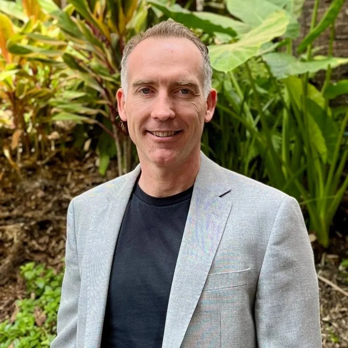 A man smiling, wearing a black t-shirt, against a white background.