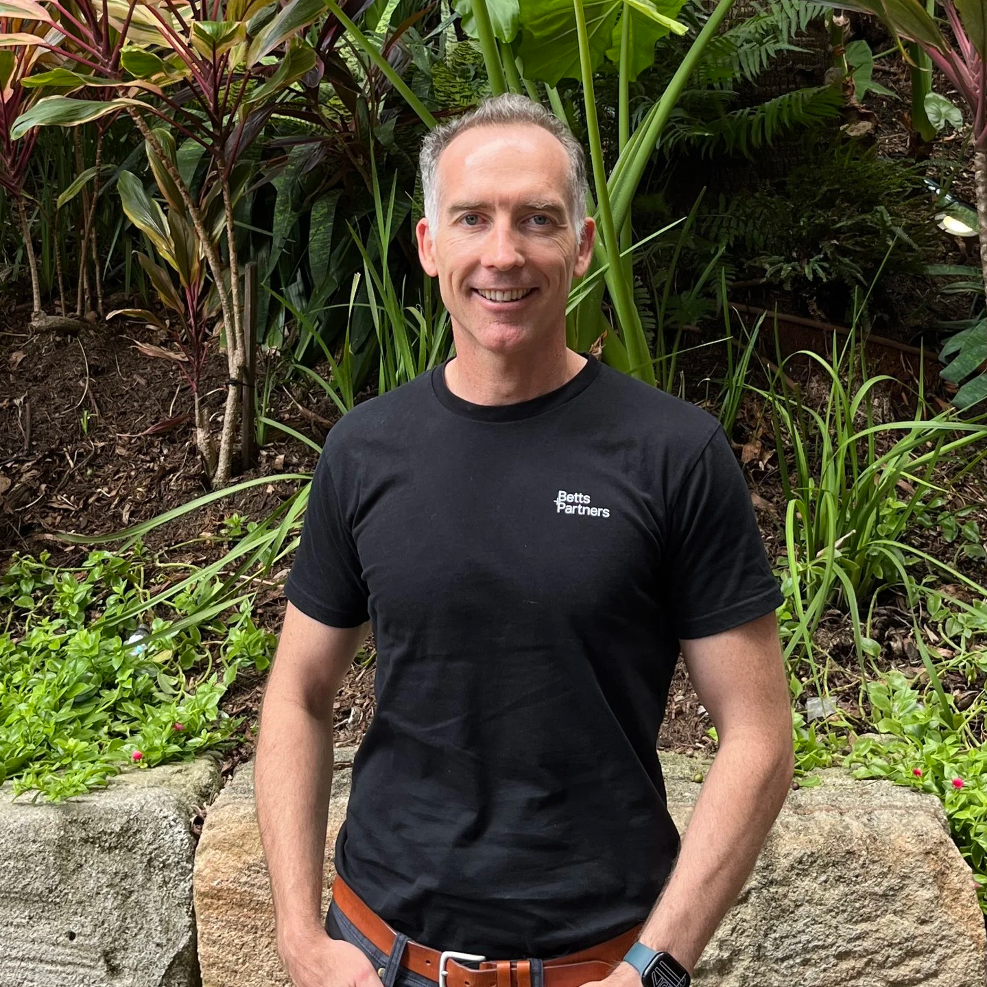 A man smiling, wearing a black t-shirt, against a white background.