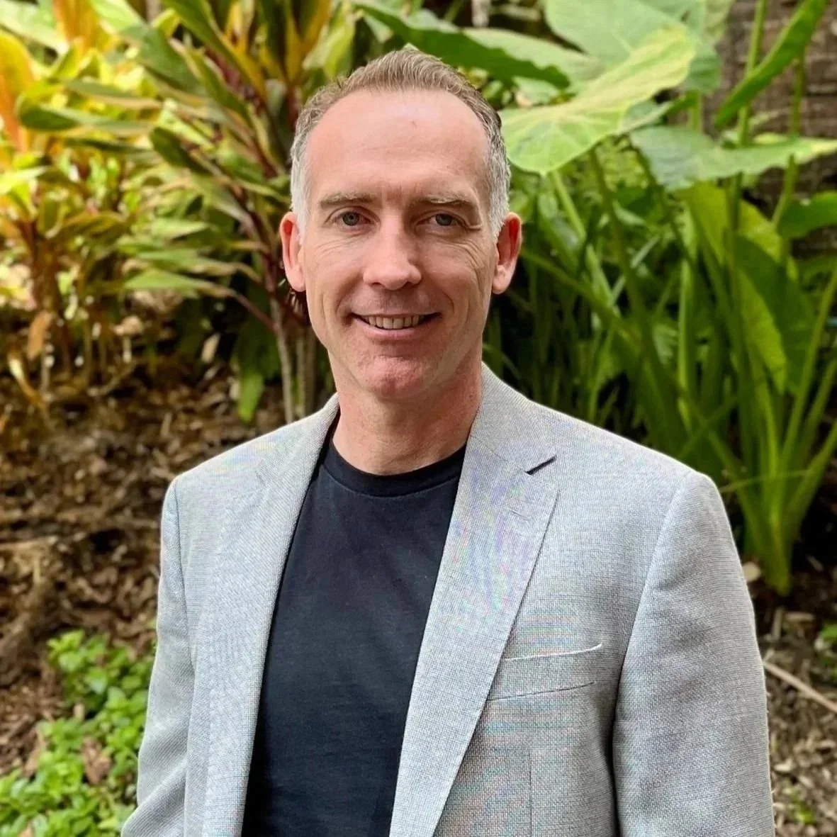 A man smiling, wearing a black t-shirt, against a white background.