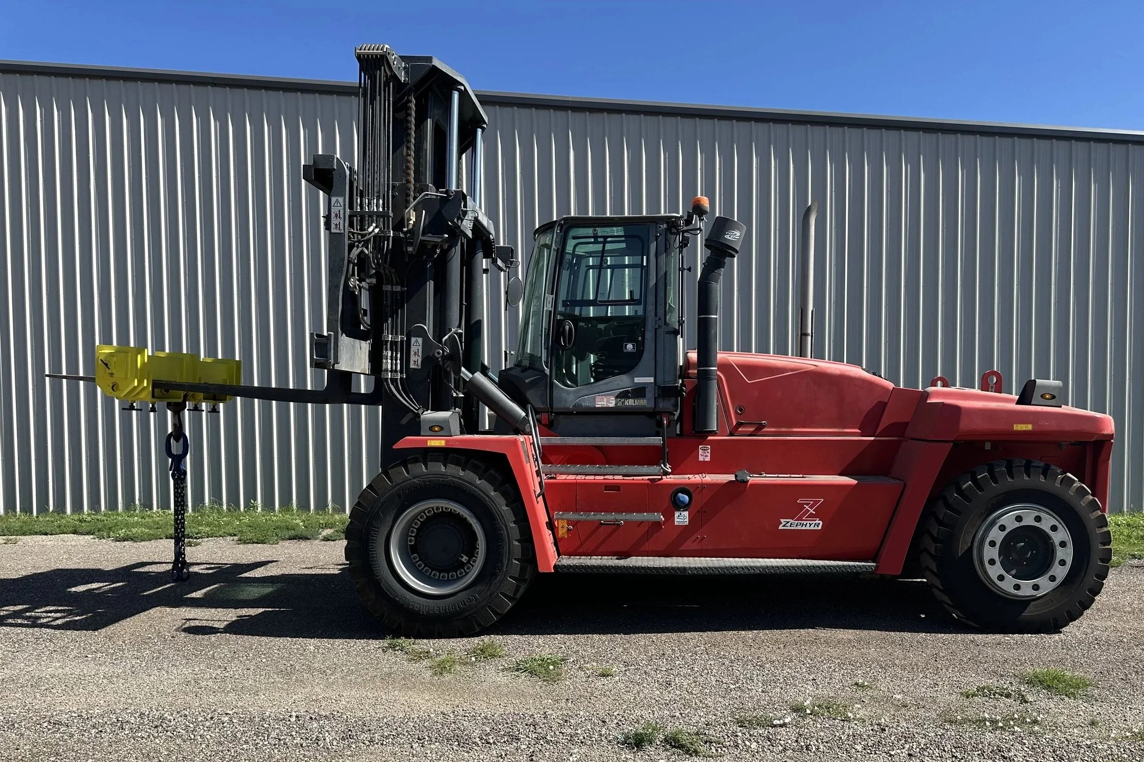 Red Zephyr forklift in front of a metal building against a clear blue sky.